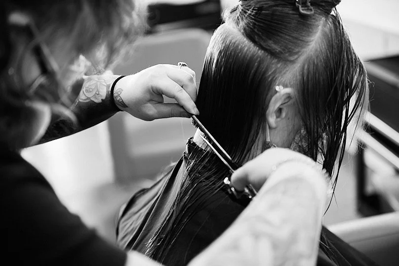 Hairdresser cutting a woman's wet hair in a salon.