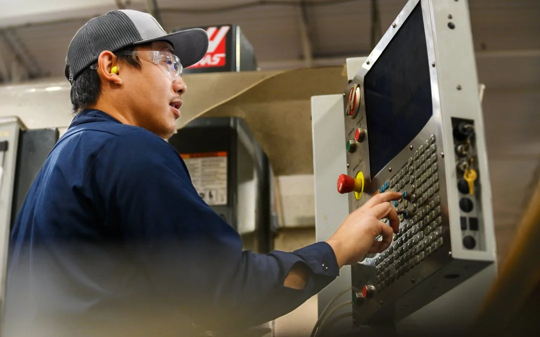 A worker operating a CNC machine in a manufacturing setting.