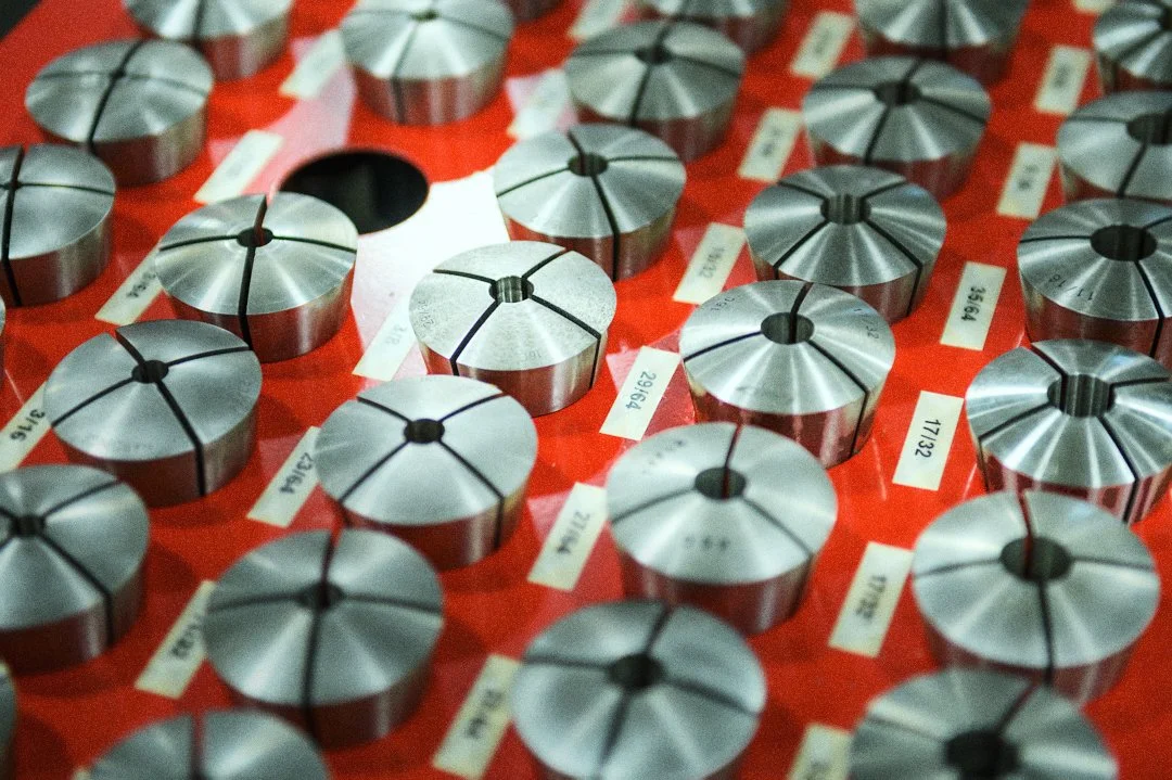 Several metal circular components with vertical slots arranged on a red surface, each labeled with white tags.