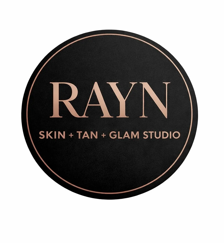 Black circular logo for RAYN, a skin, tan, and glam studio, with rose gold text and border.