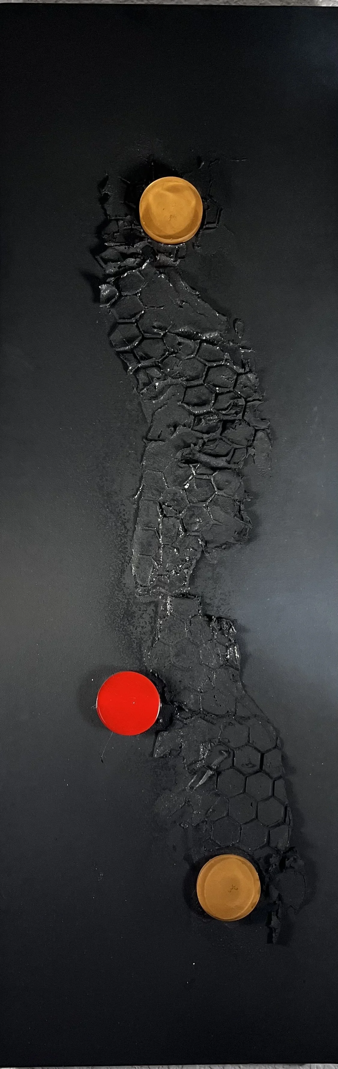 A black surface with a cracked pattern in the center, featuring two orange tokens and one red token placed on top.