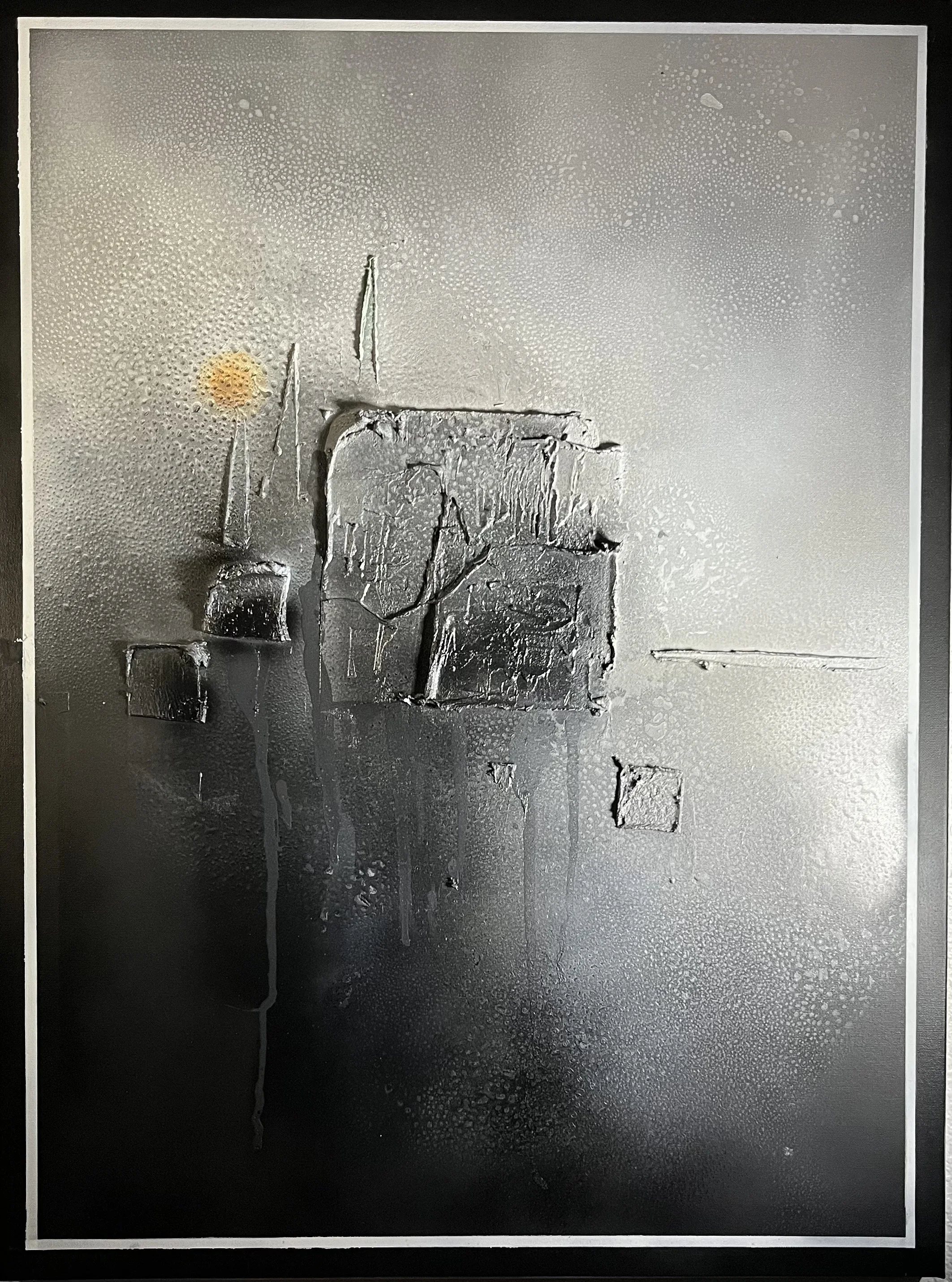 Close-up of a textured, metallic surface with black and silver tones and abstract shapes, with condensation droplets on the surface.