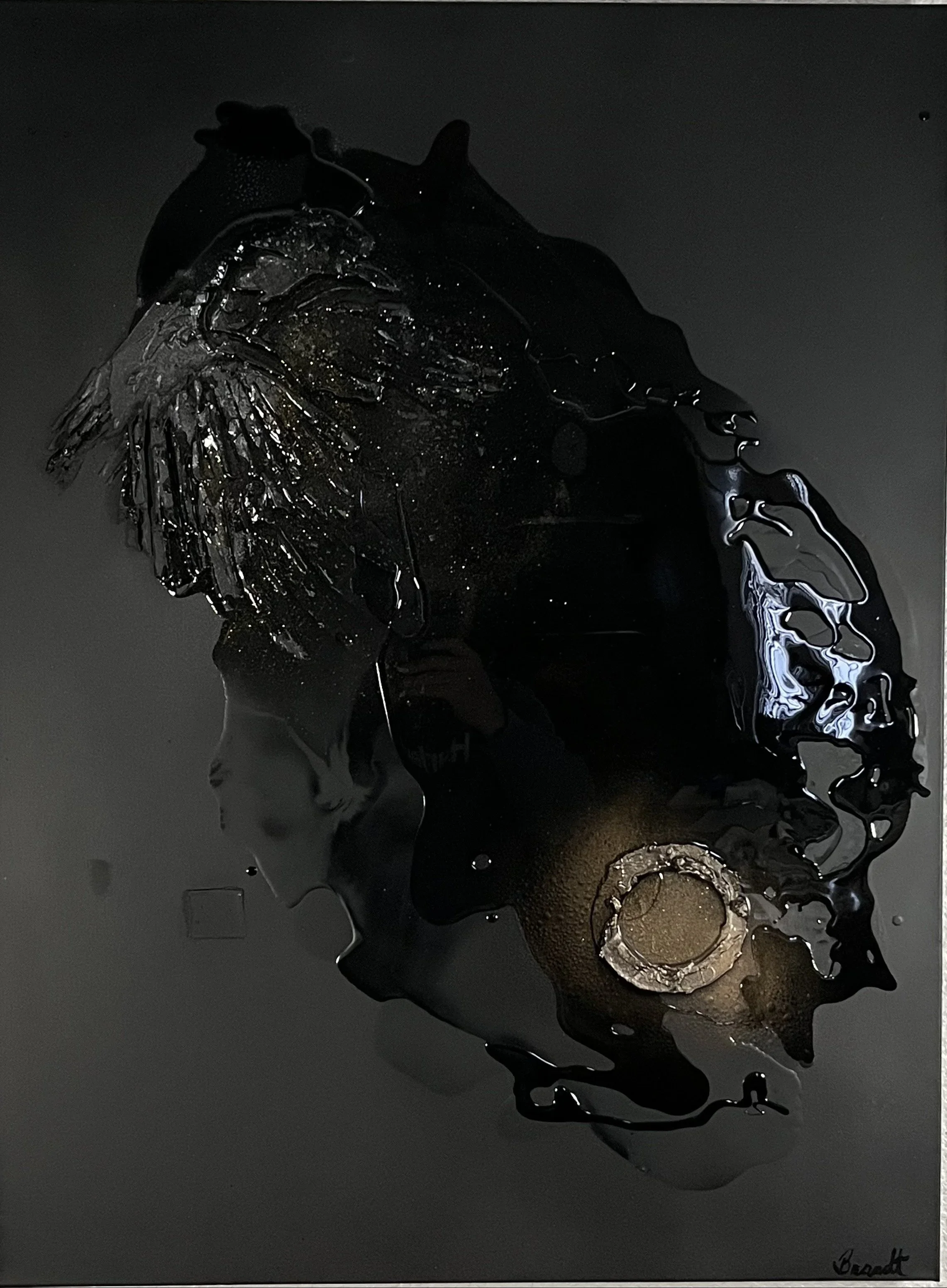 Abstract artwork featuring black paint dripped and splattered on a dark surface with metallic highlights and circular patterns.