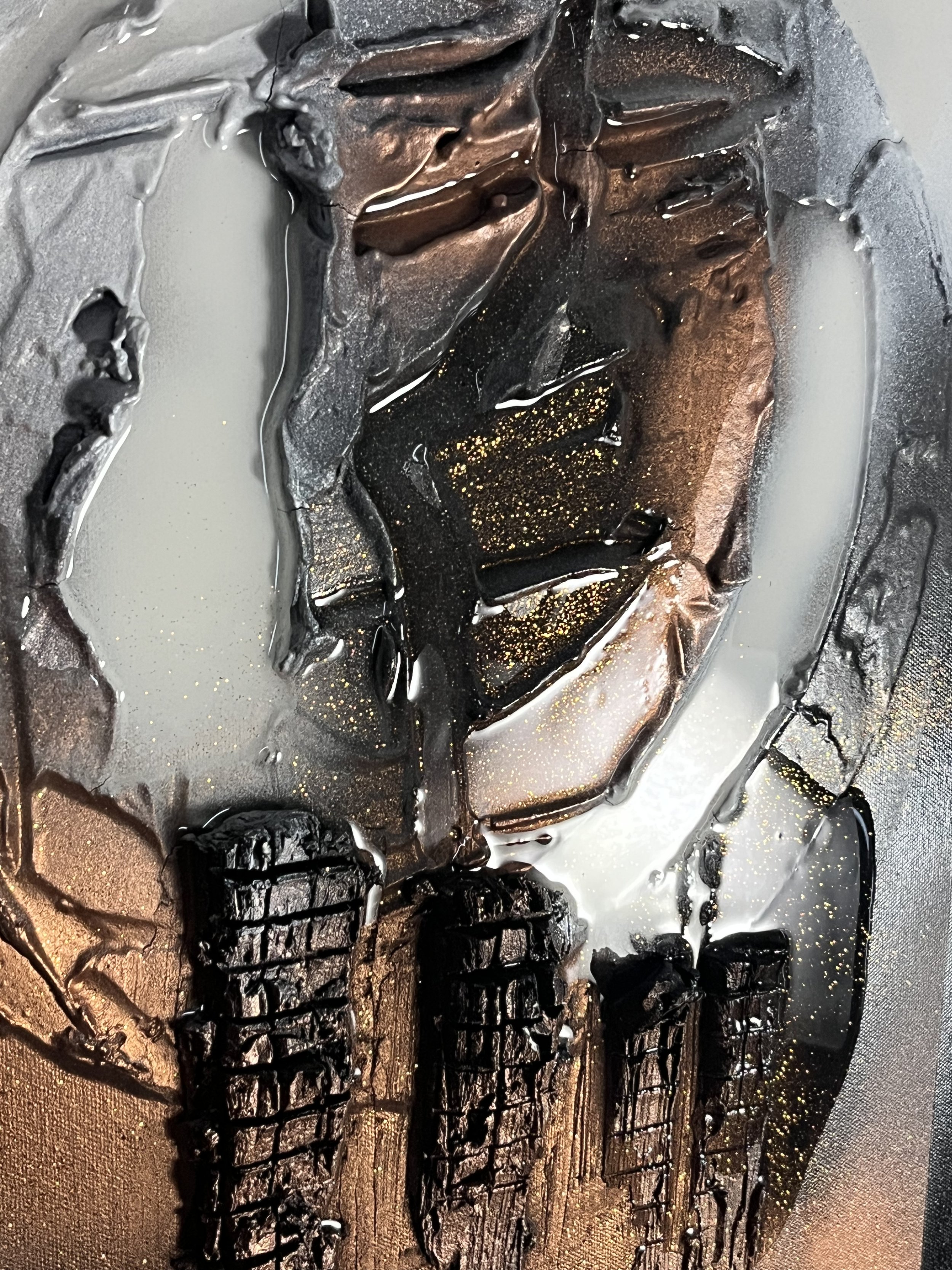Close-up of a monochrome painted artwork, featuring abstract textures including black, gold, and gray tones with a metallic sheen, and intricate details of cracked and layered paint.