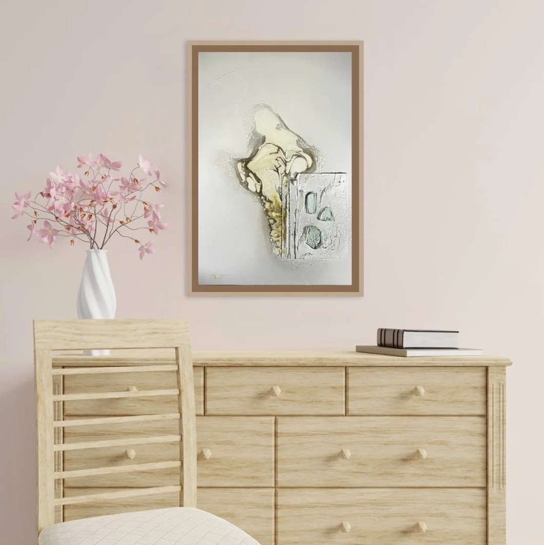 A modern bedroom corner with a light wooden dresser, a white chair, a white vase with pink artificial flowers on the dresser, a framed abstract painting hanging on the wall, and a few books on the dresser.