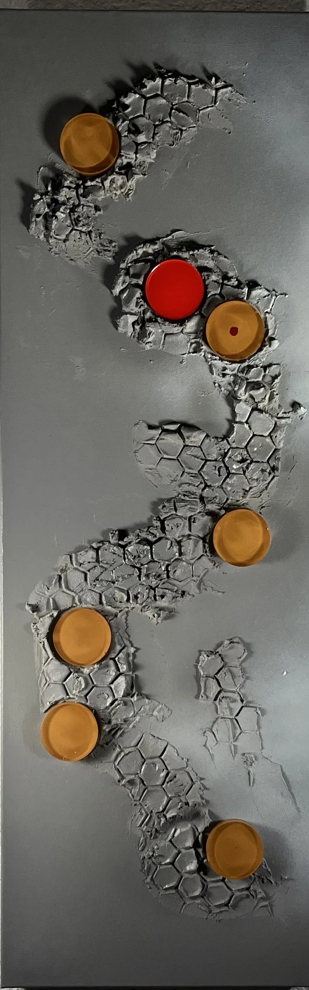 Wall with holes and honeycomb pattern, five orange lids and one red lid attached, creating an abstract design.
