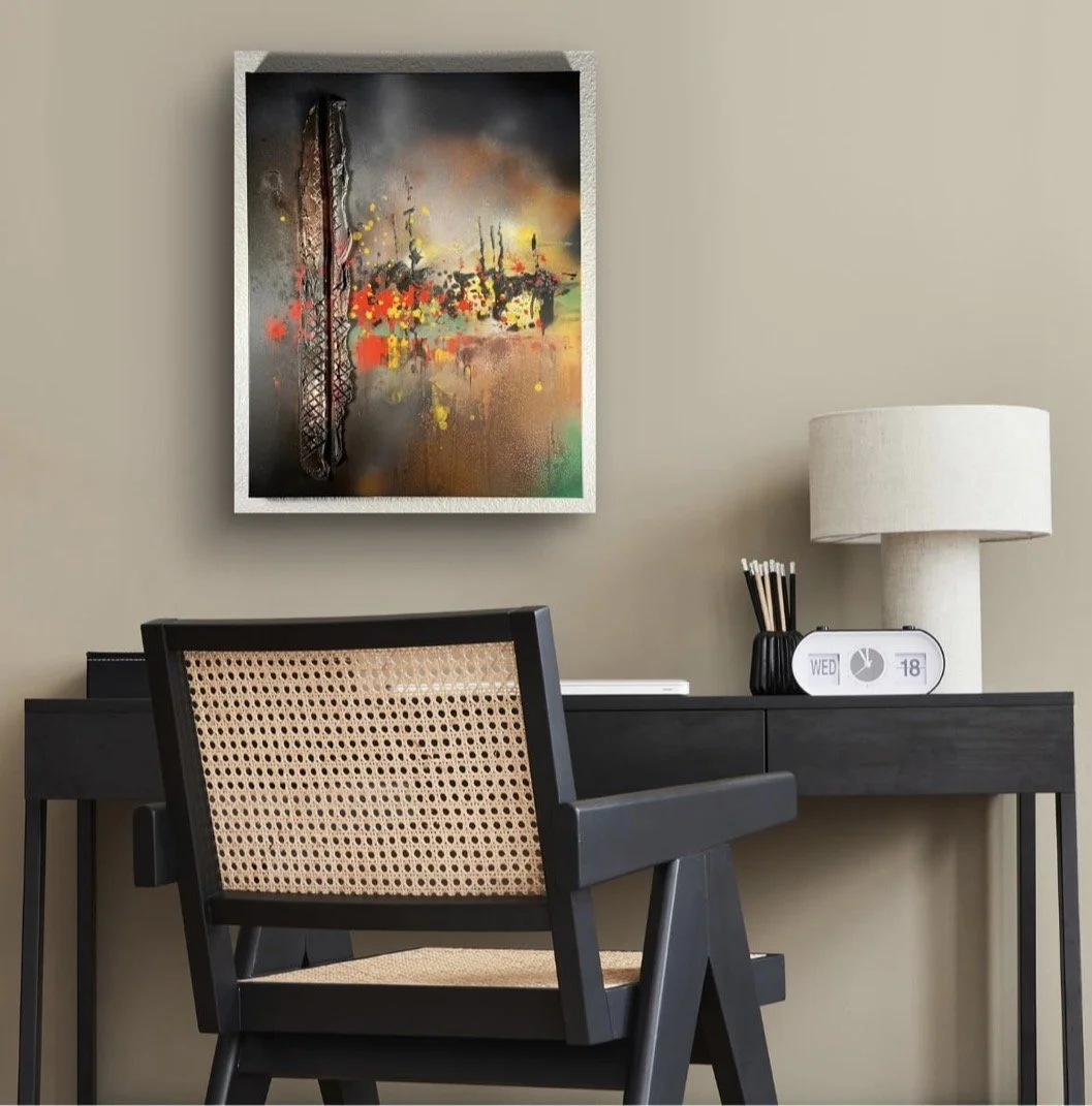 A modern workspace with a black desk, a black chair with woven cane backrest, a beige lamp, a digital clock, and a colorful abstract painting on a beige wall.