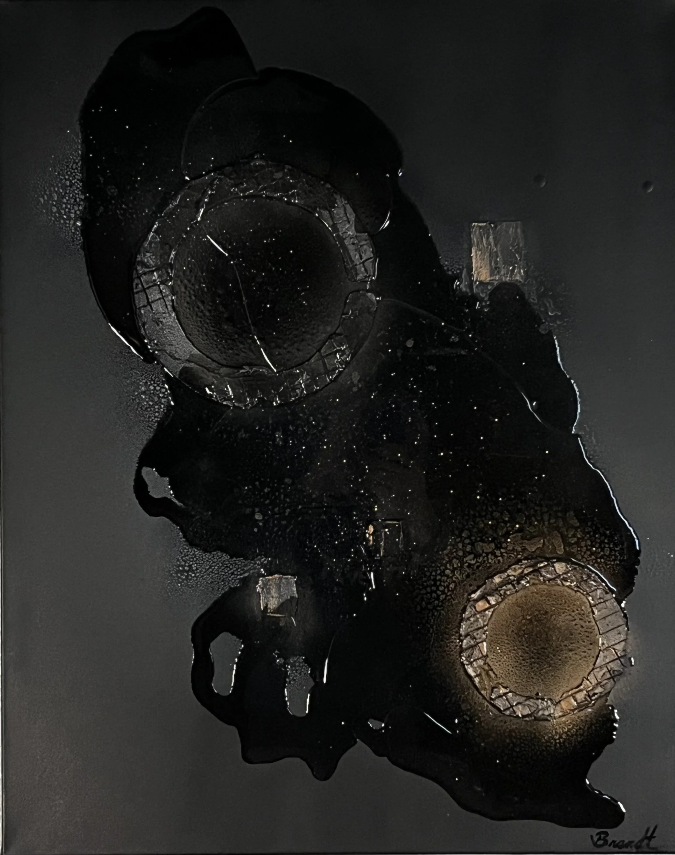 Artistic black and gold abstract painting featuring circular and organic shapes with textured details on a dark background.