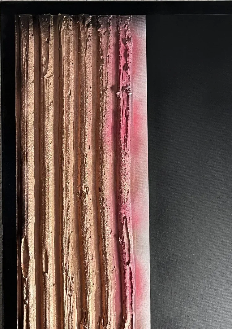 Close-up of a textured, multi-layered, frosted cake with pink icing, displayed on a black surface.