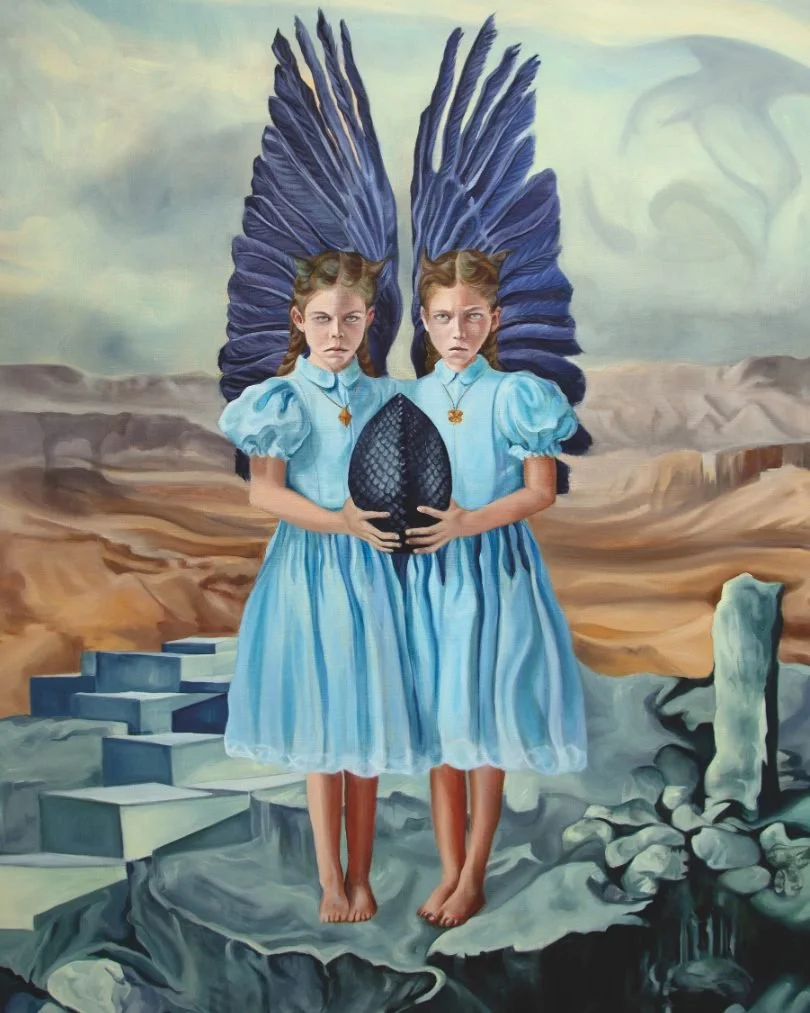 To unge piger med blå kjoler og store blå fjerbure på ryggen står på en klippe og holder en stor sort æg. I baggrunden er der et tørt, ørkenlignende landskab med nogle trin og sten.