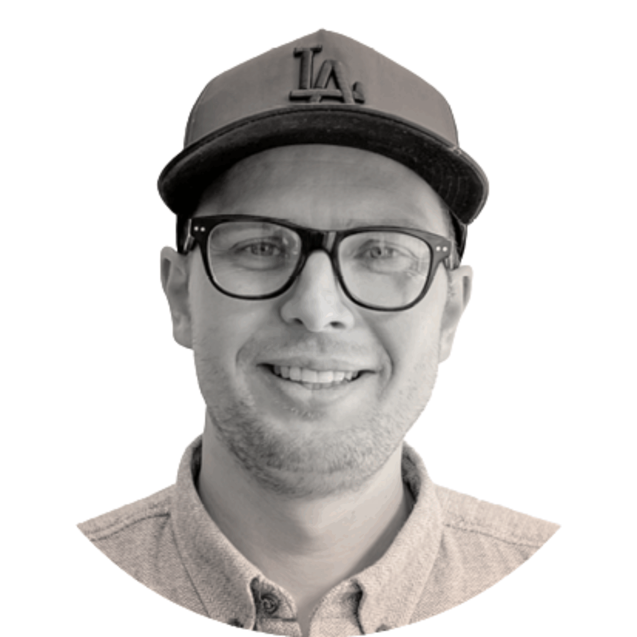 Black and white portrait of a person wearing glasses, a cap with an 'LA' logo, and a suit jacket, smiling.