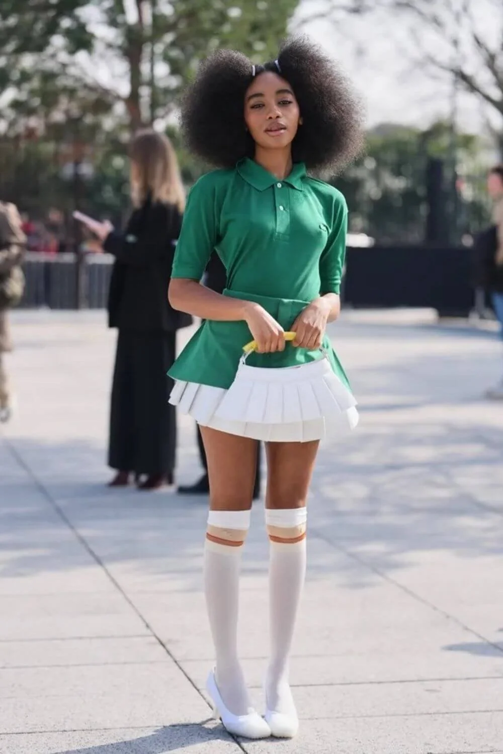 Green knit polo paired with a white pleated mini skirt and knee-high socks