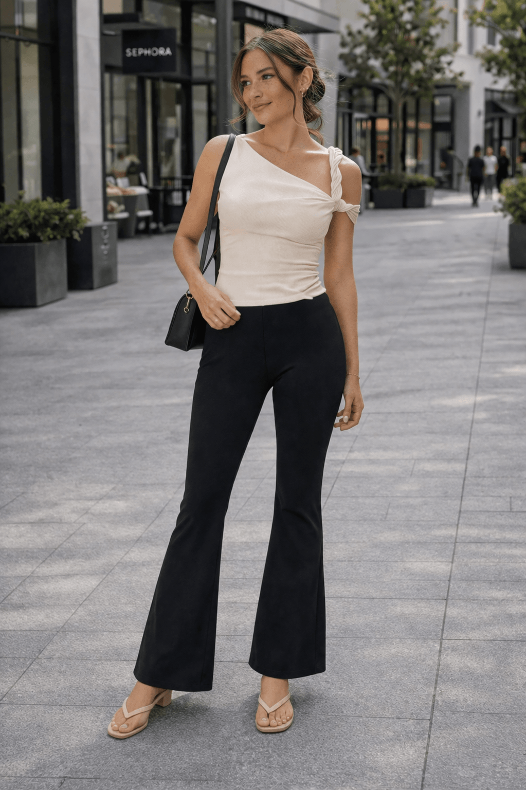 Black flare leggings styled with a cream asymmetrical top and nude thong kitten heel sandals for a polished casual outfit