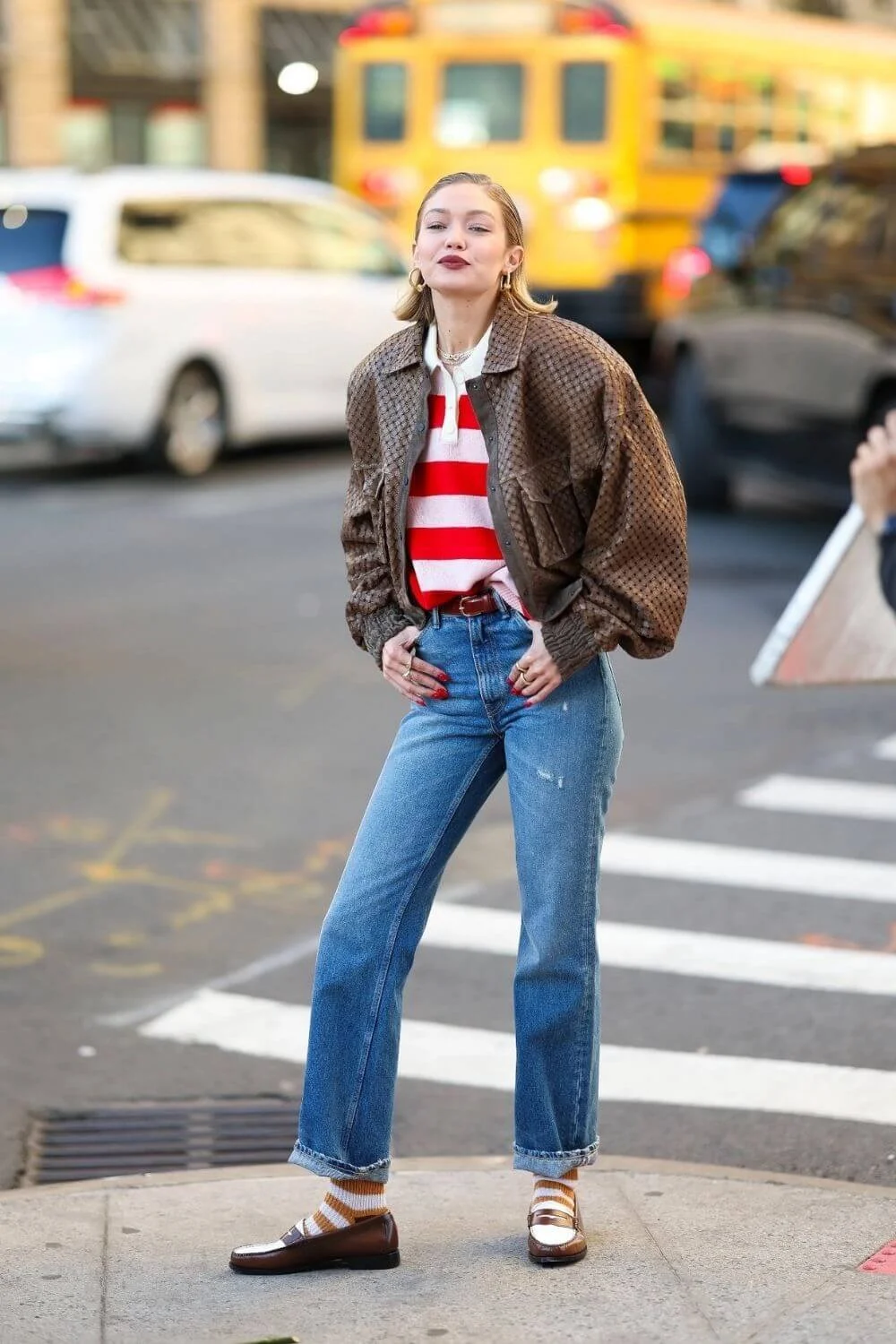 Striped knit polo layered under a brown bomber jacket with blue jeans