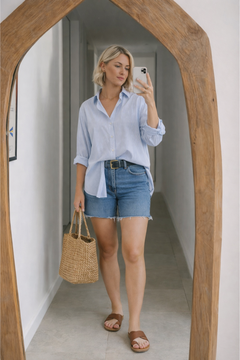 spring outfit with oversized blue button down shirt and denim shorts styled with brown sandals