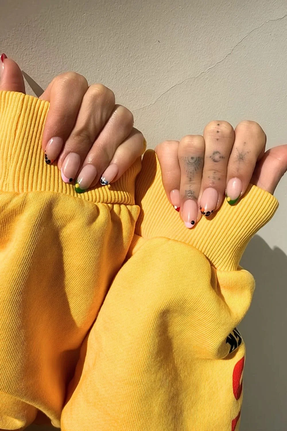 Hailey Bieber minimal French manicure at Coachella with sheer nude base and small colorful tip accents