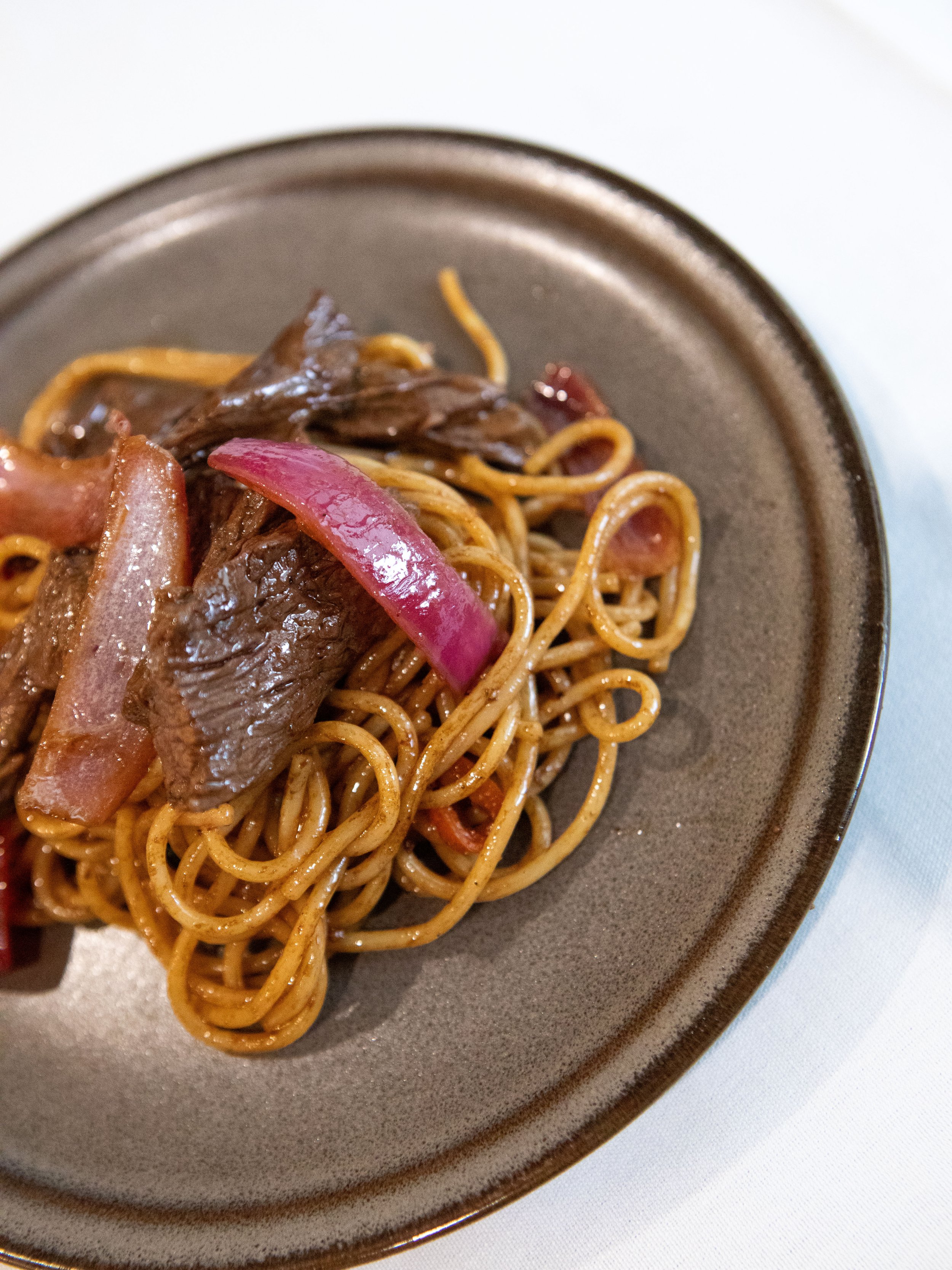Plate of beef and vegetable stir-fry with noodles on a brown plate