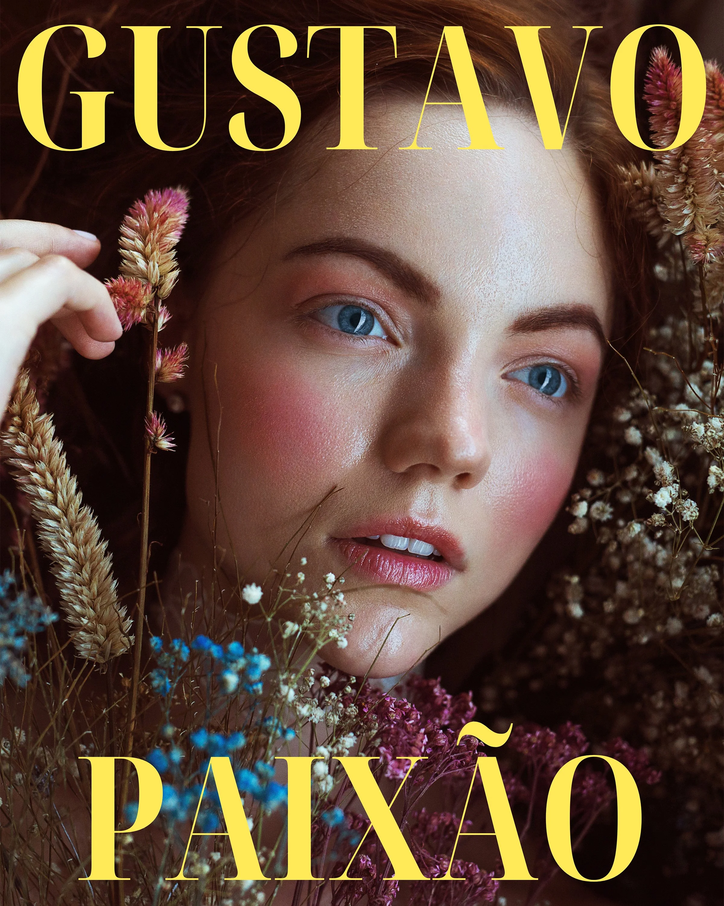 A close-up portrait of a woman with blue eyes and pink makeup, surrounded by various colorful dried flowers and plants.