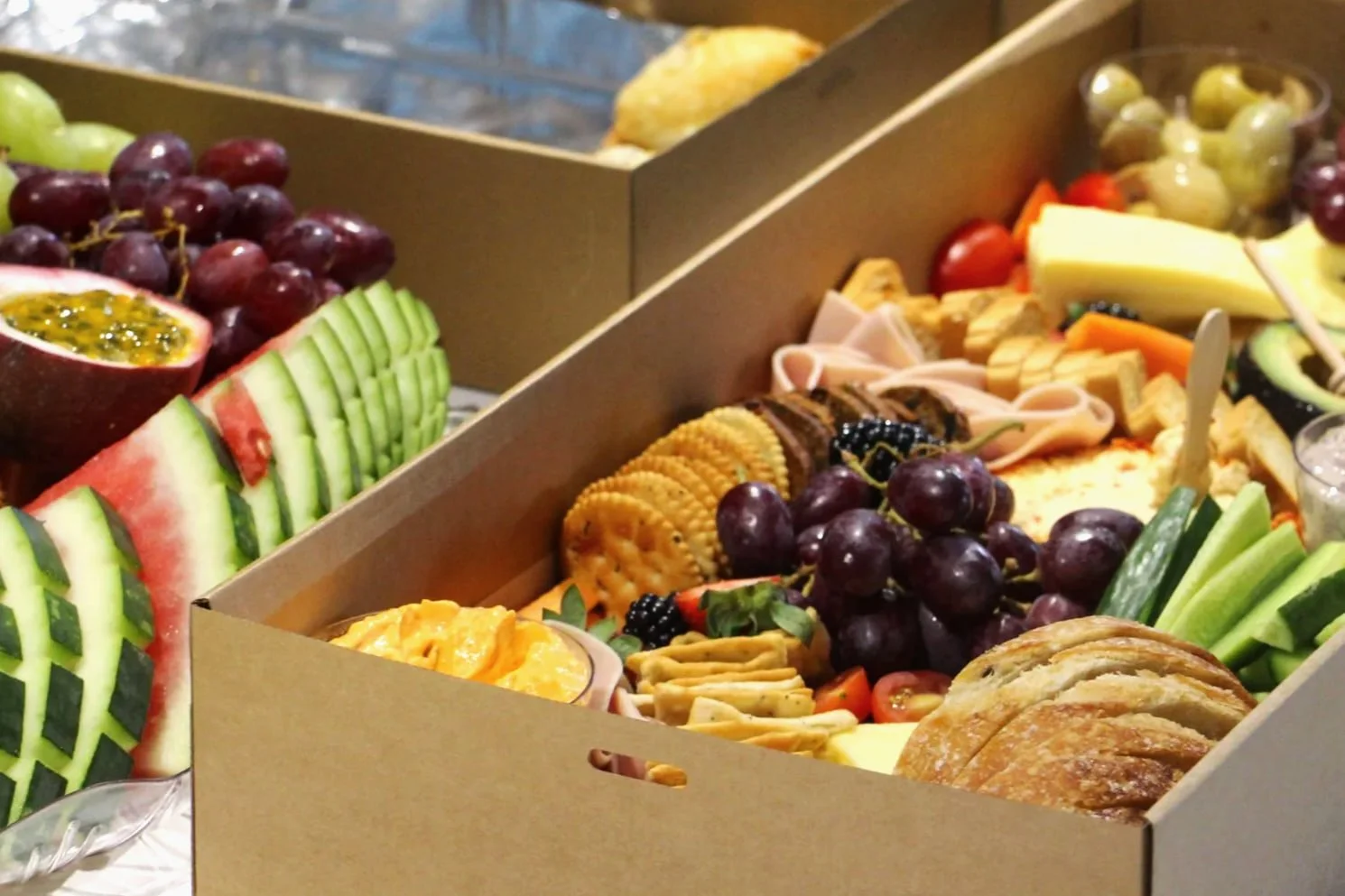 Grazing boxes filled with fruit, cheese, crackers and bread at an engagement party