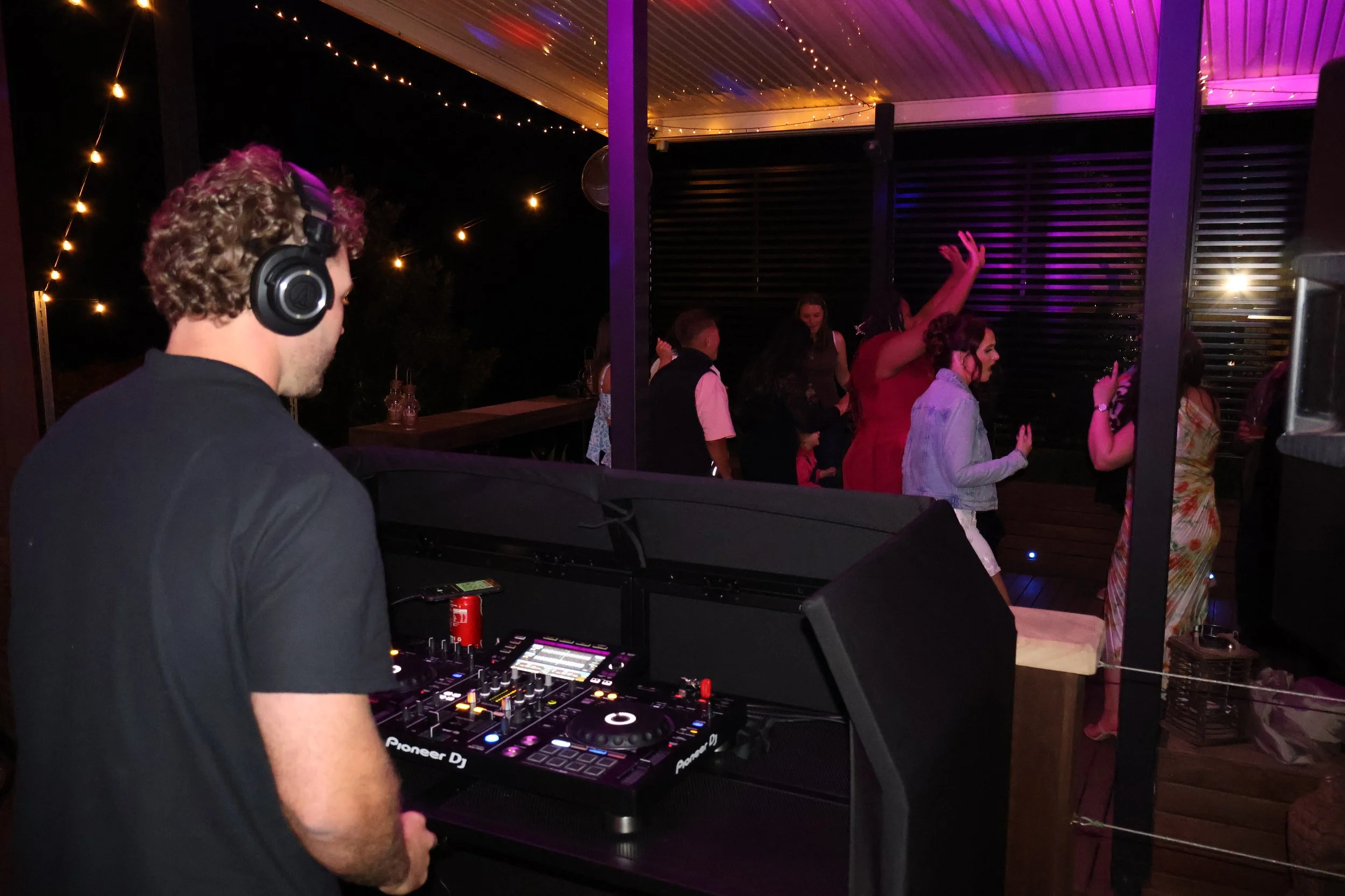 On Cue DJ performing under purple lights at a rural engagement party