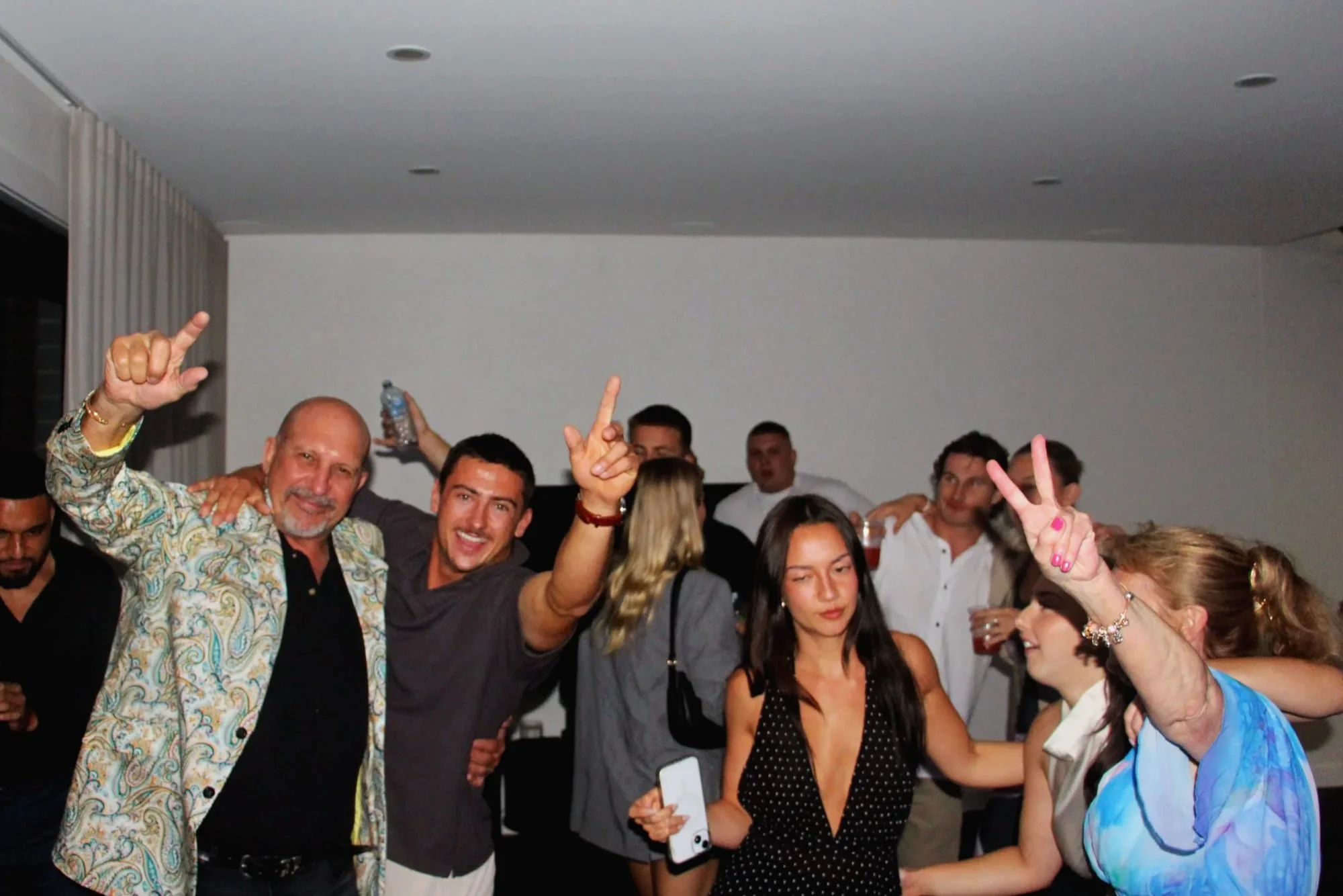 Engagement party guests celebrating and pointing to the ceiling on the dancefloor