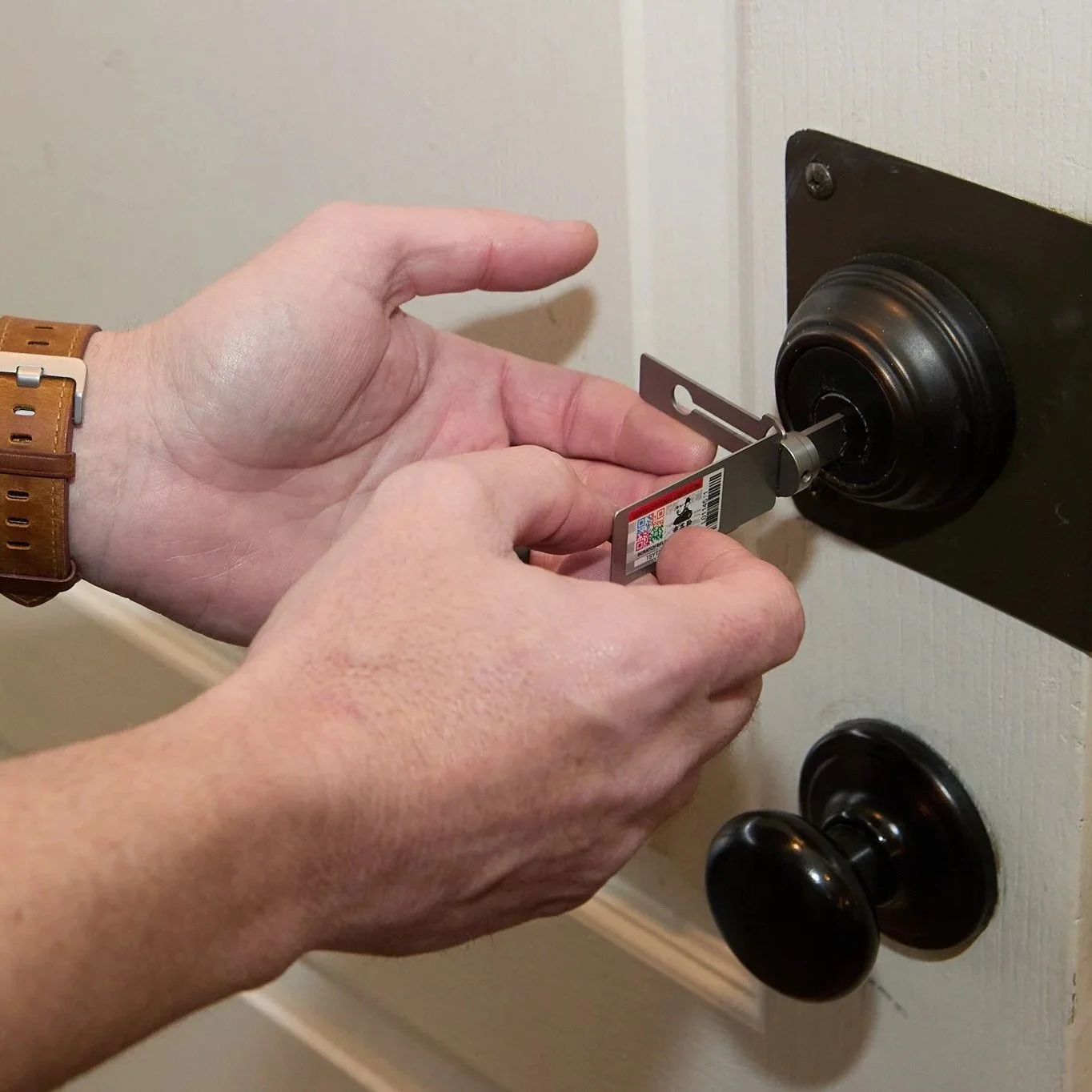 Close-up of a locksmith inspecting a residential door lock cylinder using a tool to assess internal wear and key operation.