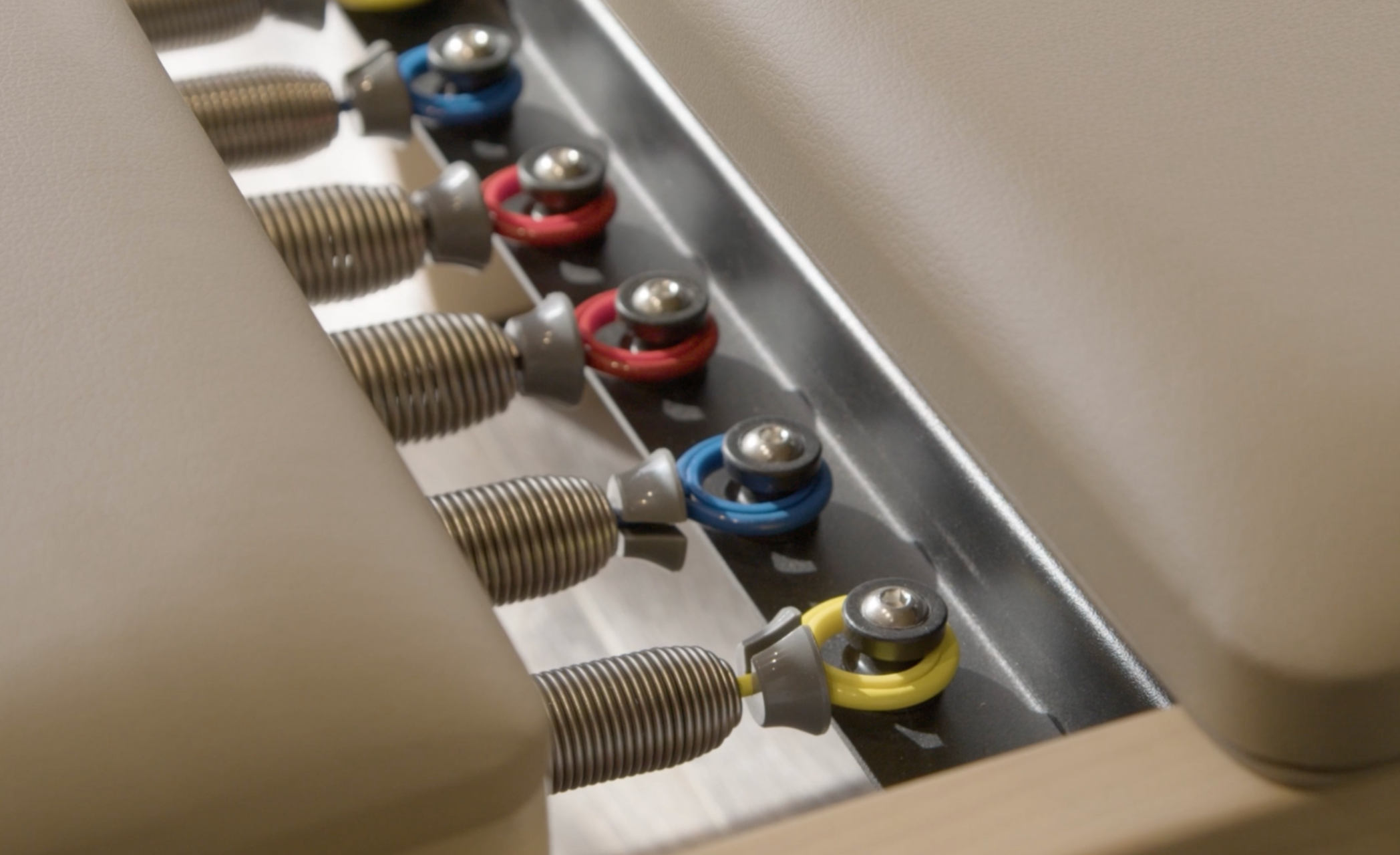 Close-up of a row of color-coded electrical wires connected to metal ports with coil connectors.