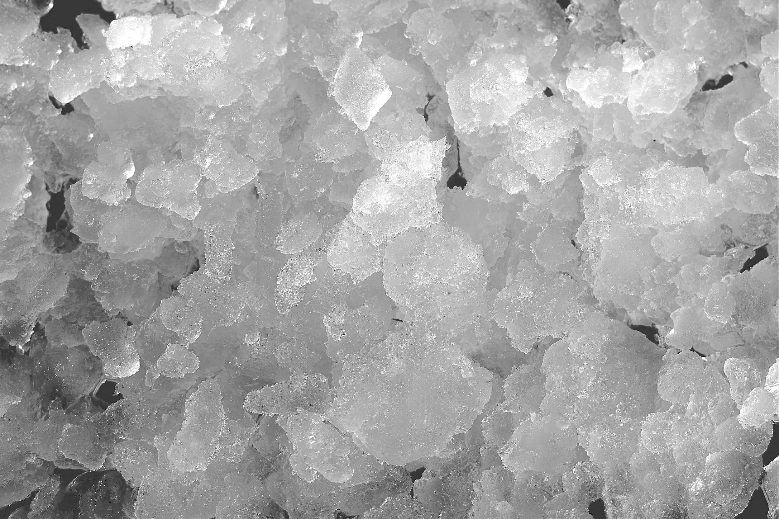 Close-up of white crystalline salt crystals scattered on a surface.