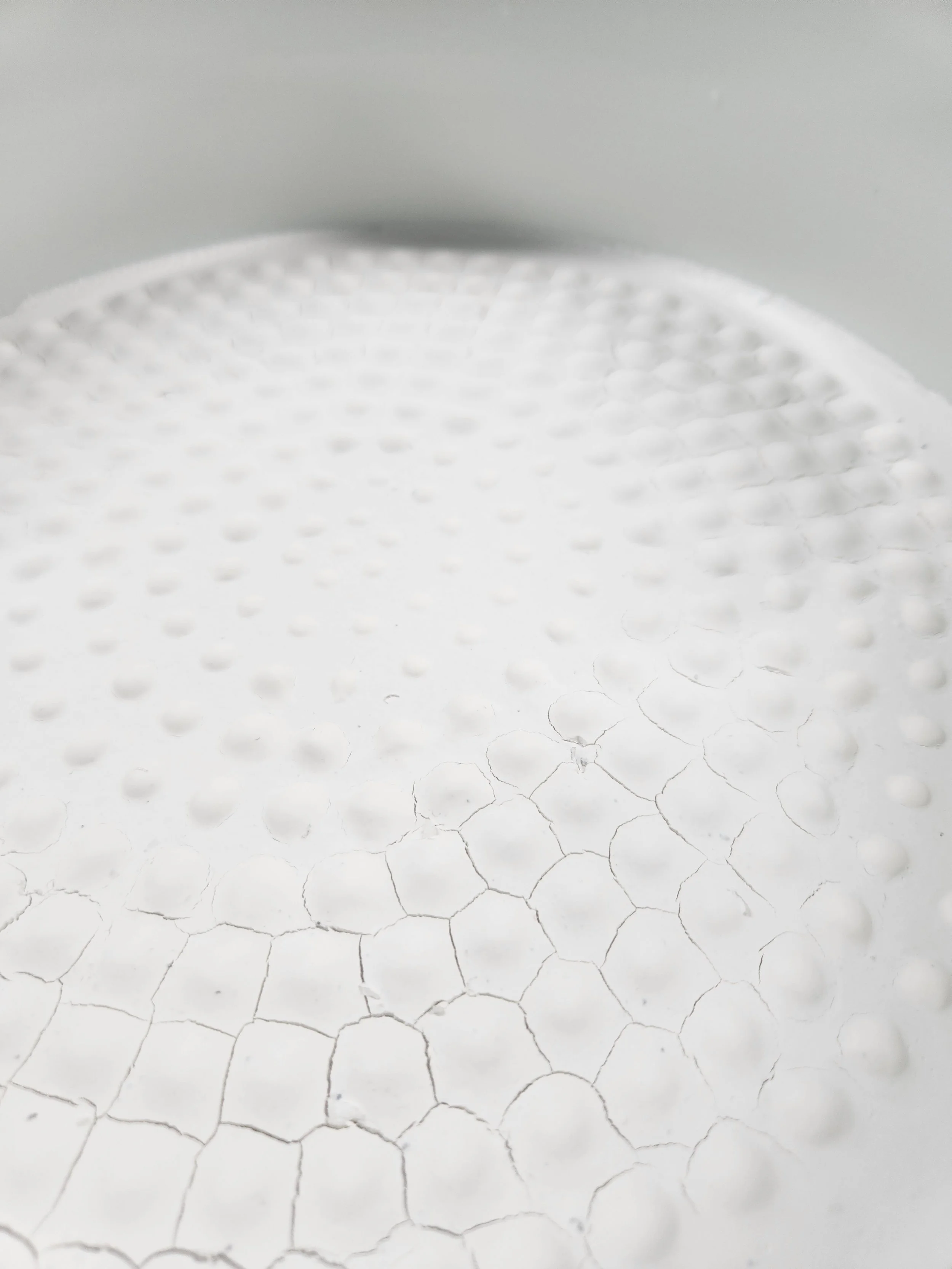 A close-up of a white craft foam surface with textured dots and a cracked, honeycomb pattern.