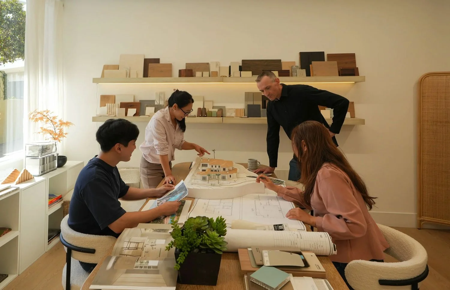 JH2 Architects team analyzing a model home on a table in their head office