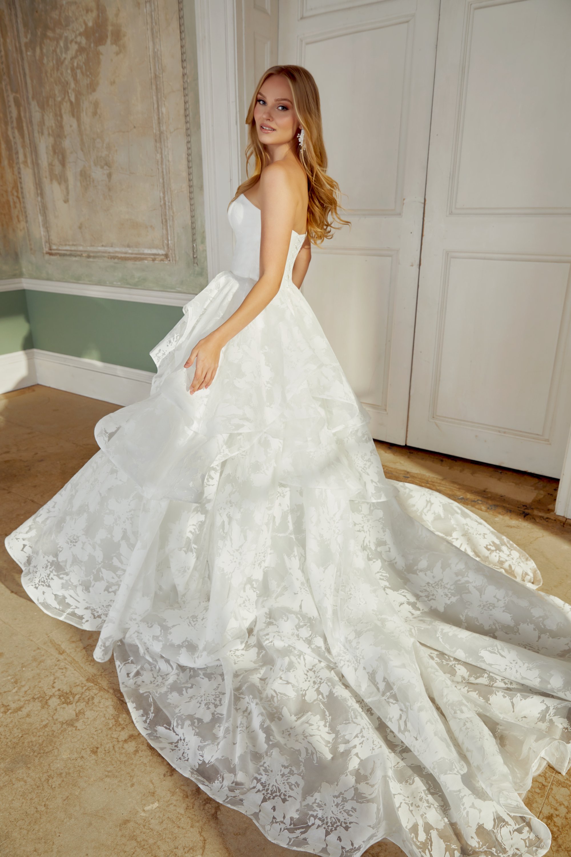 Mujer con vestido de novia en un salón elegante con paredes decoradas y puerta blanca.