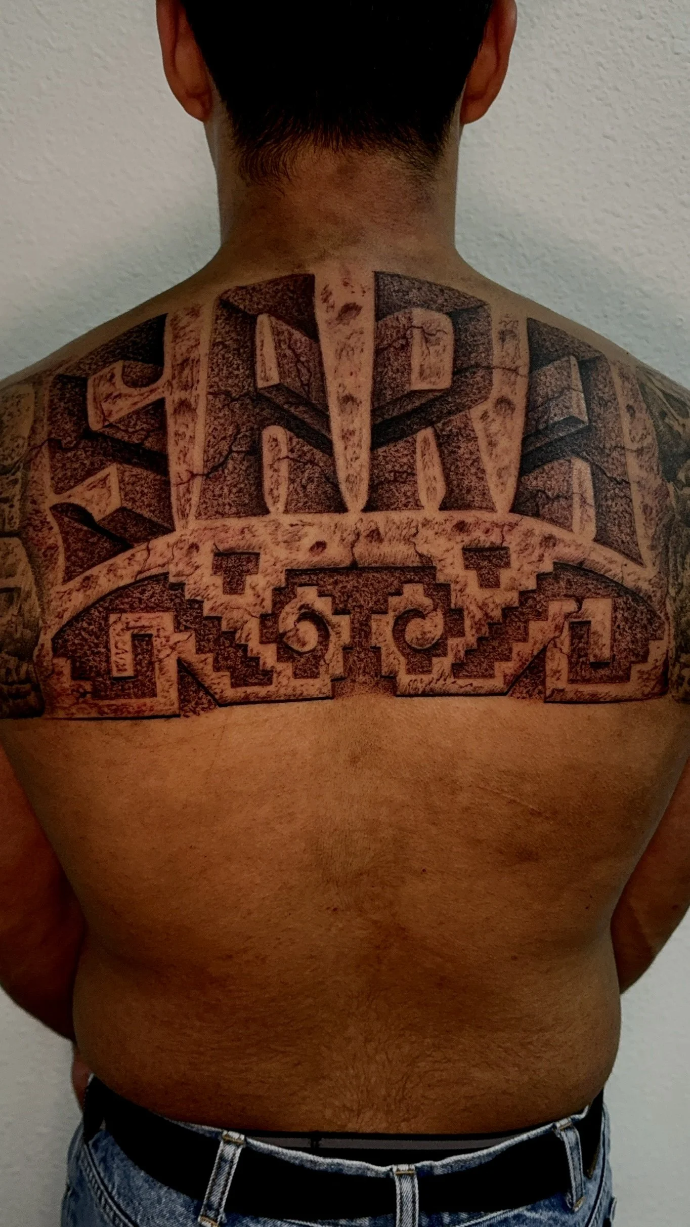 Last name back tattoo with aztec ornament