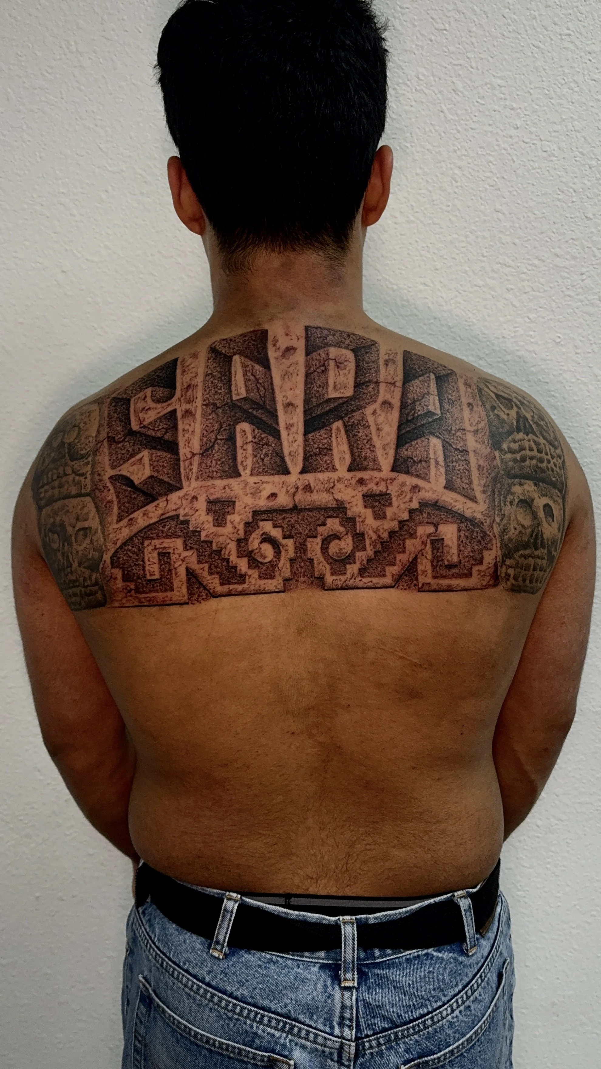 Sara last name back tattoo with aztec skulls