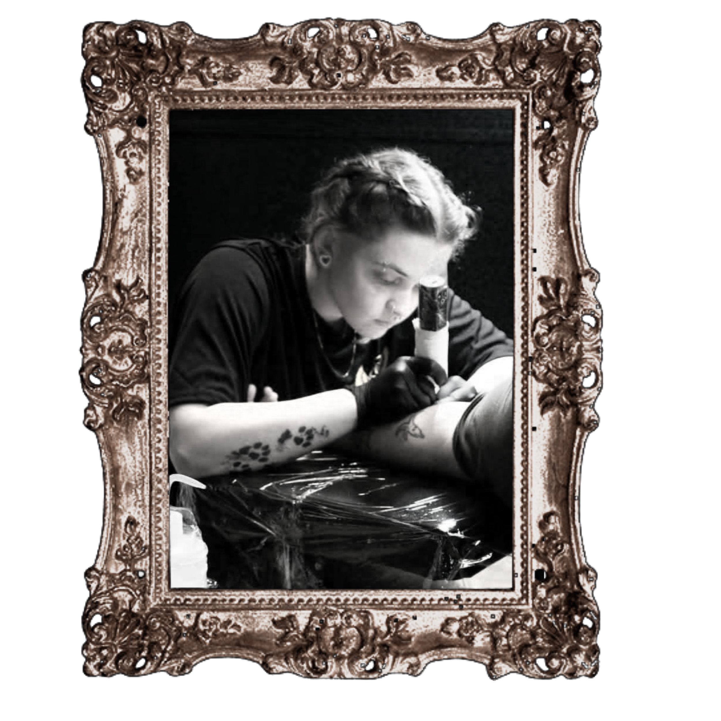 Black-and-white photo of a woman with short, light-colored hair and glasses, reading a book inside a large, ornate frame with intricate floral designs.