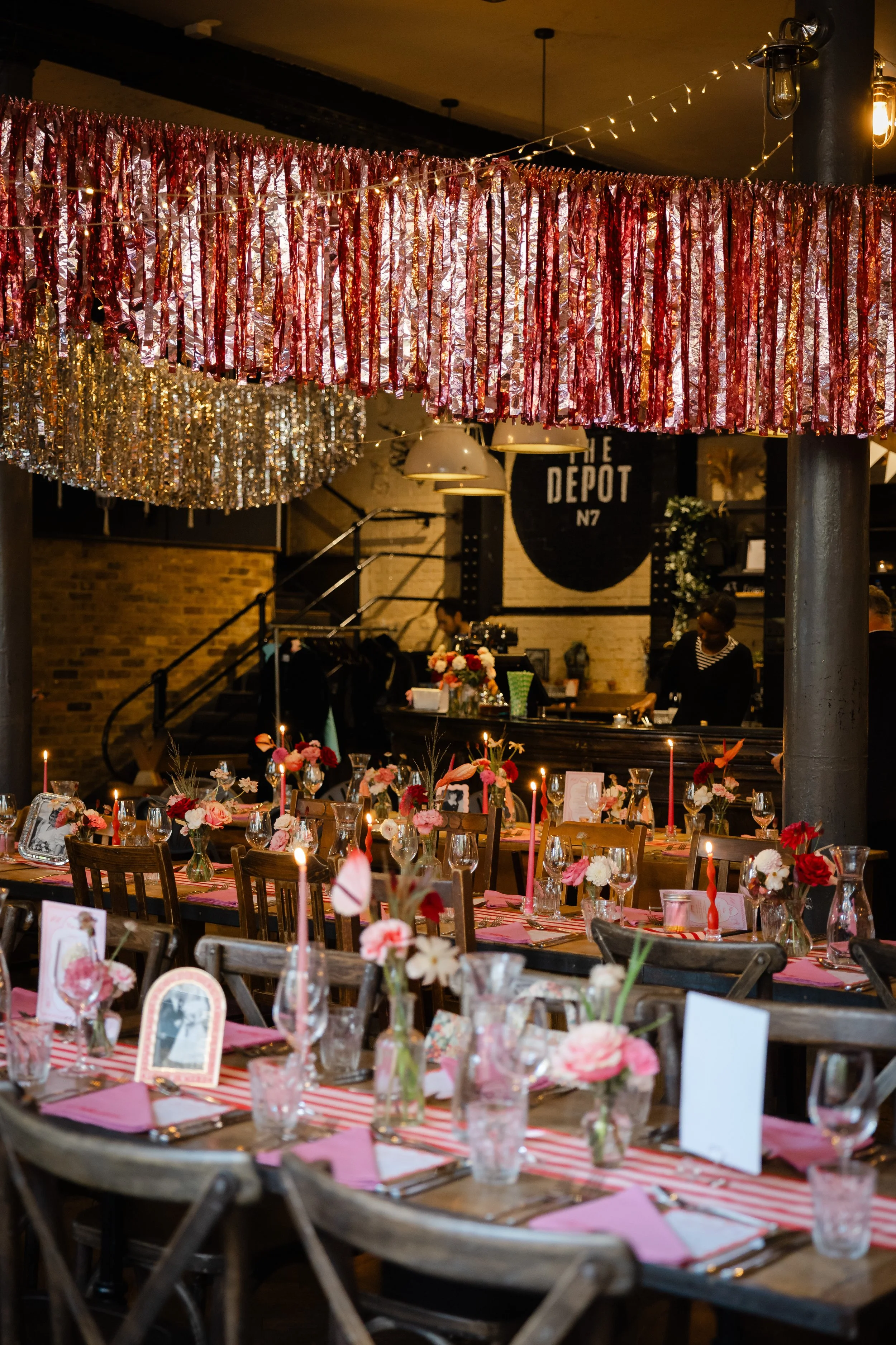 Decorated dining area with floral arrangements and pink candles at a party or celebration