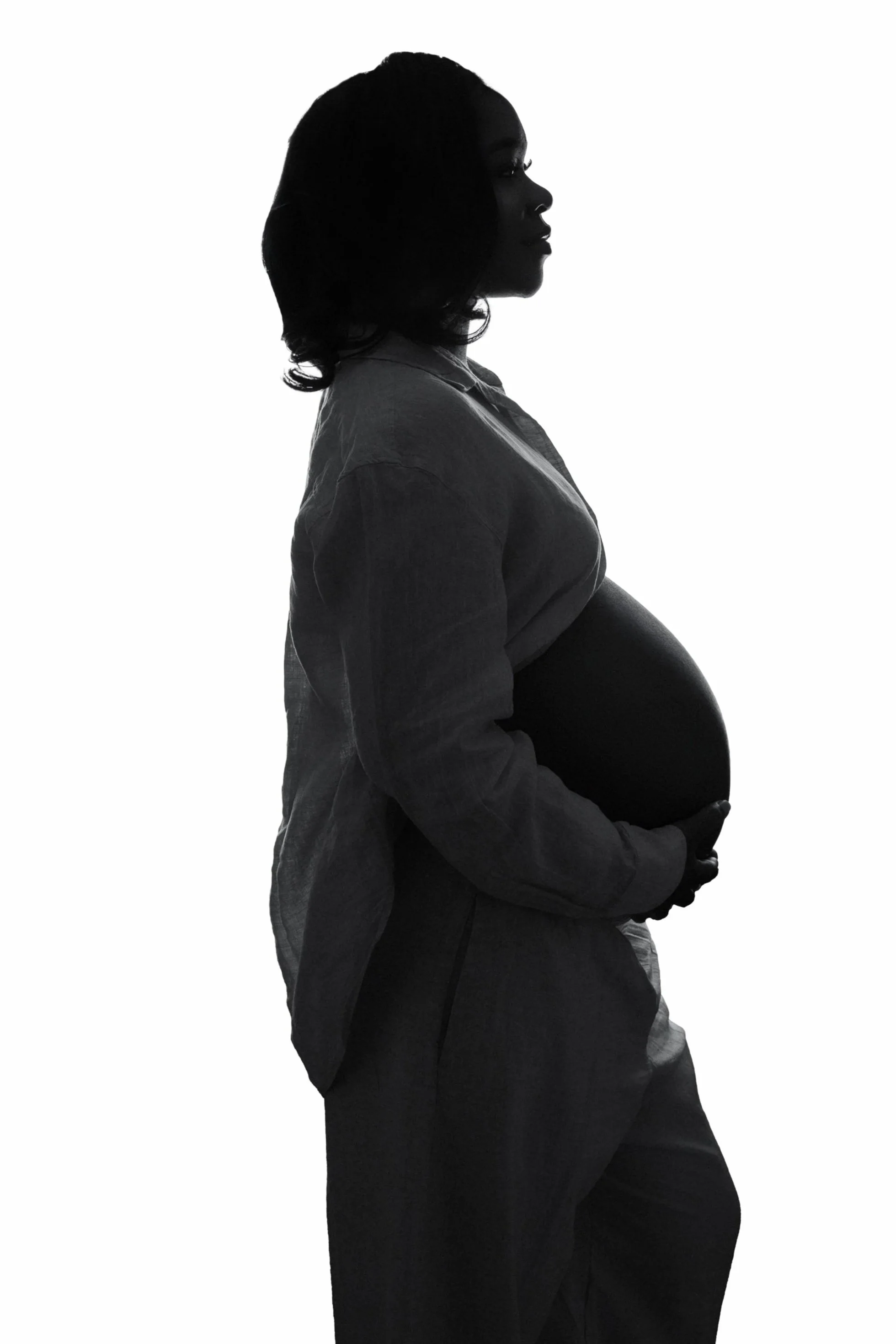 Silhouette of a pregnant woman in profile holding her belly against a white background.
