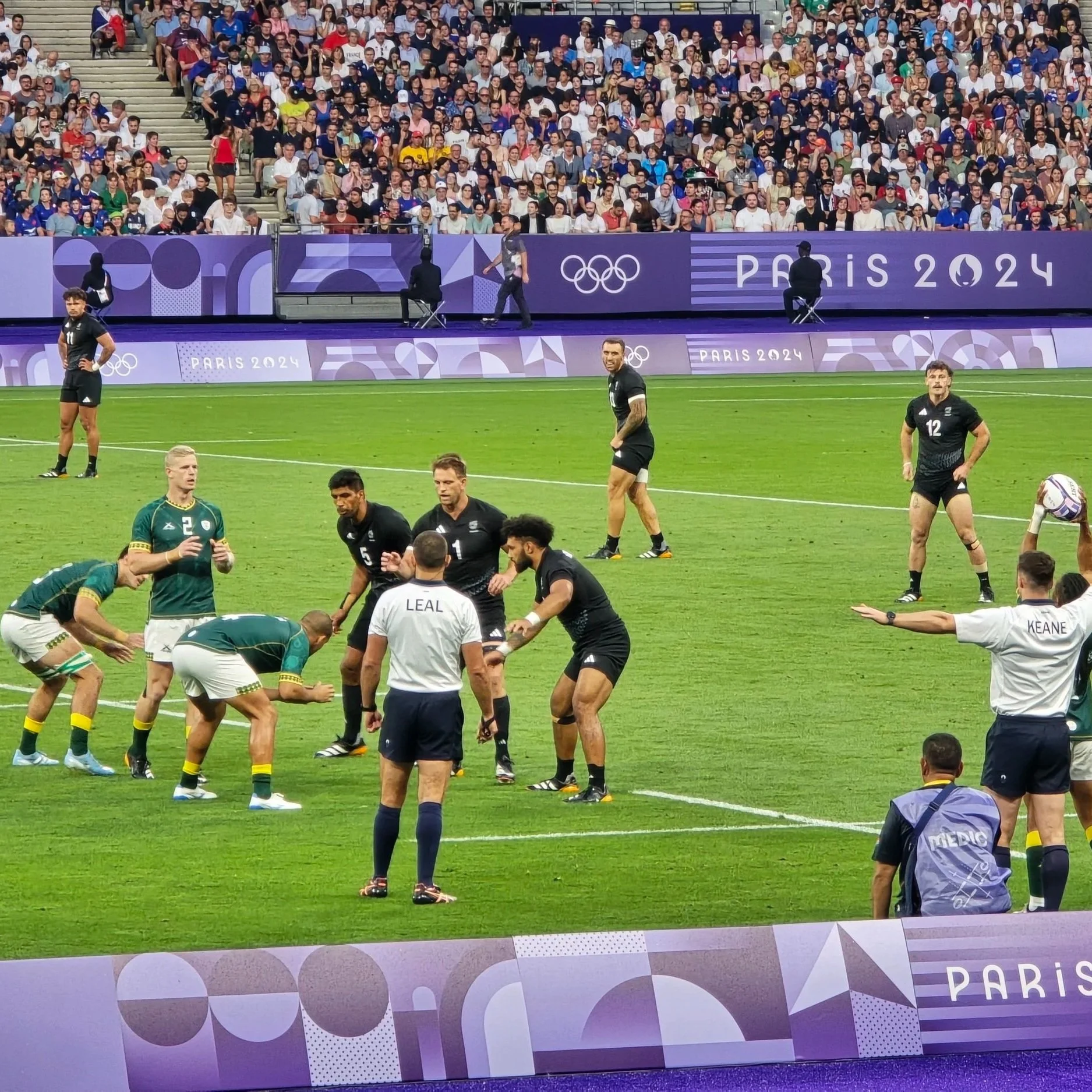 Olympic rugby match at Paris 2024, Springbok and all Black players on the field during a line-out with crowd in stands in the background