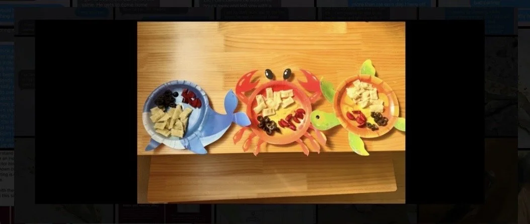 Fish theme plates with toddler snacks on a wood table 