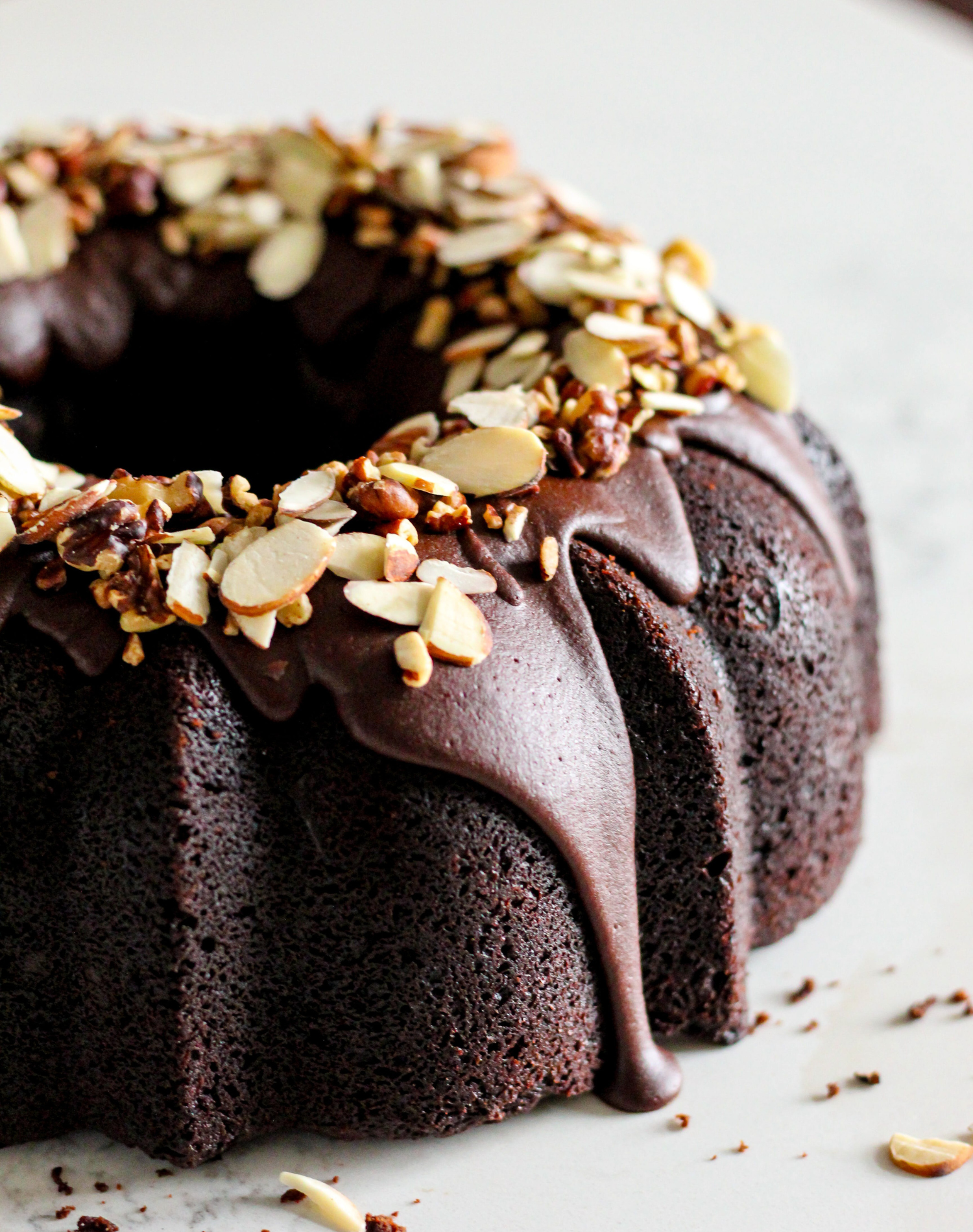 Close-up of a chocolate bundt cake topped with almond slices and chocolate glaze