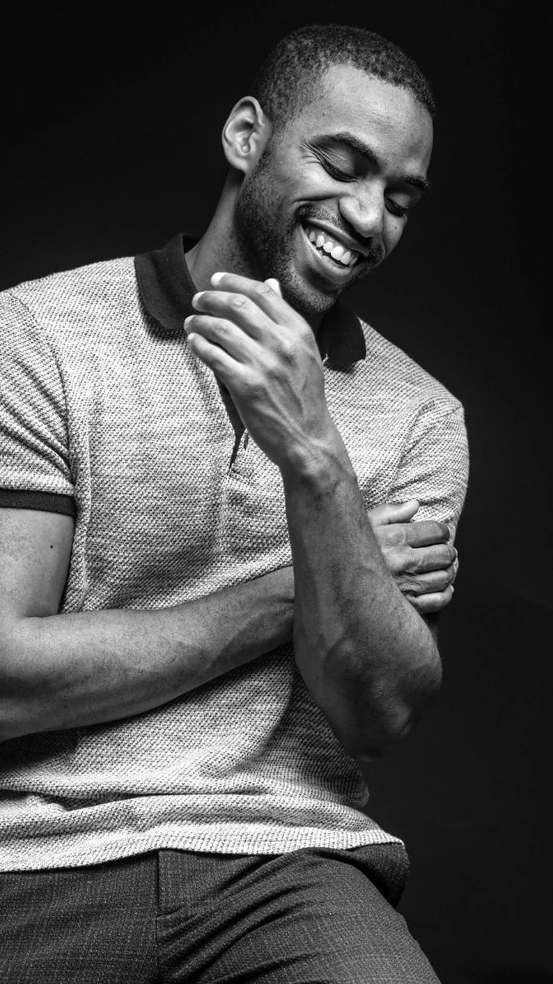 A portrait of a smiling man in a polo shirt touching his chin in a thoughtful, grounded posture.