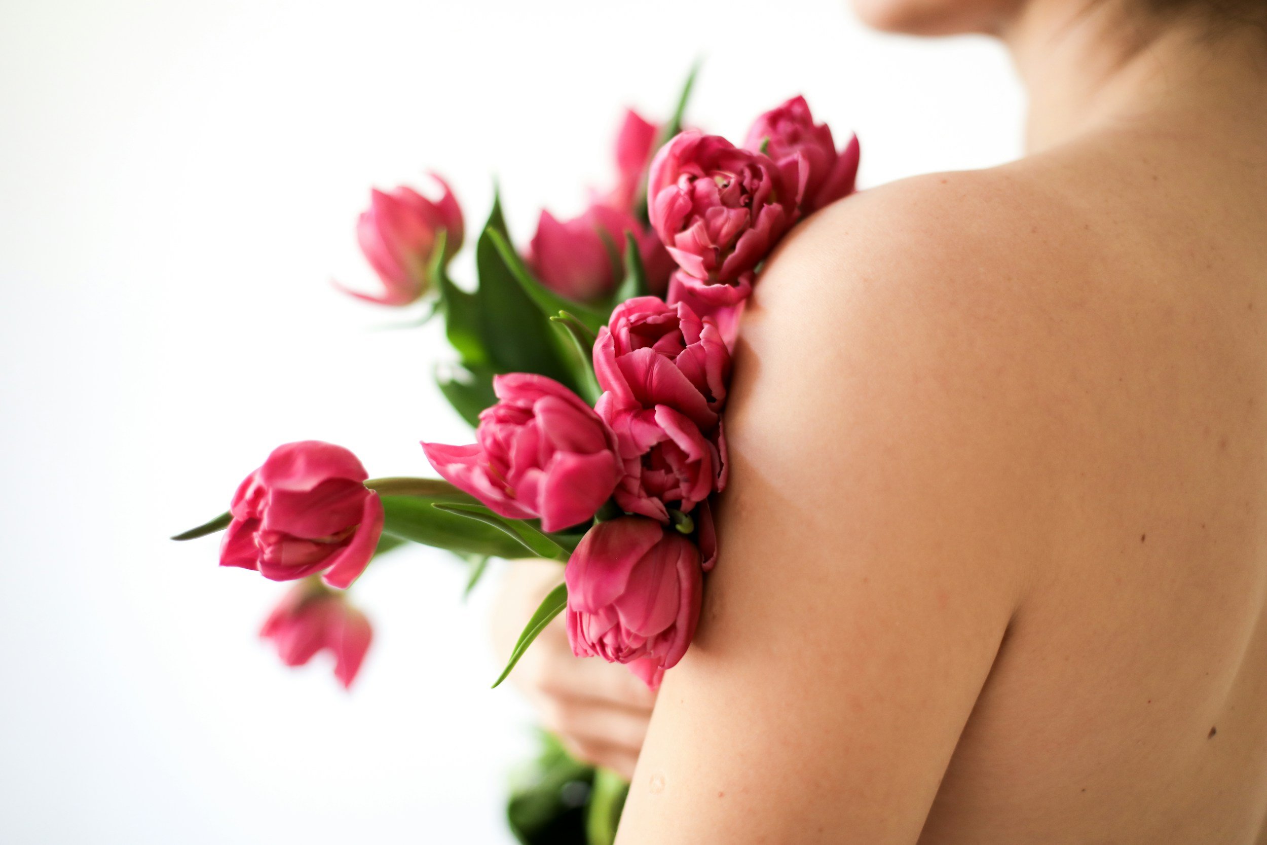 Somatic sex coaching for women and vulva owners, featuring a grounded sensory photo of a person with pink flowers to represent pleasure and intimacy.