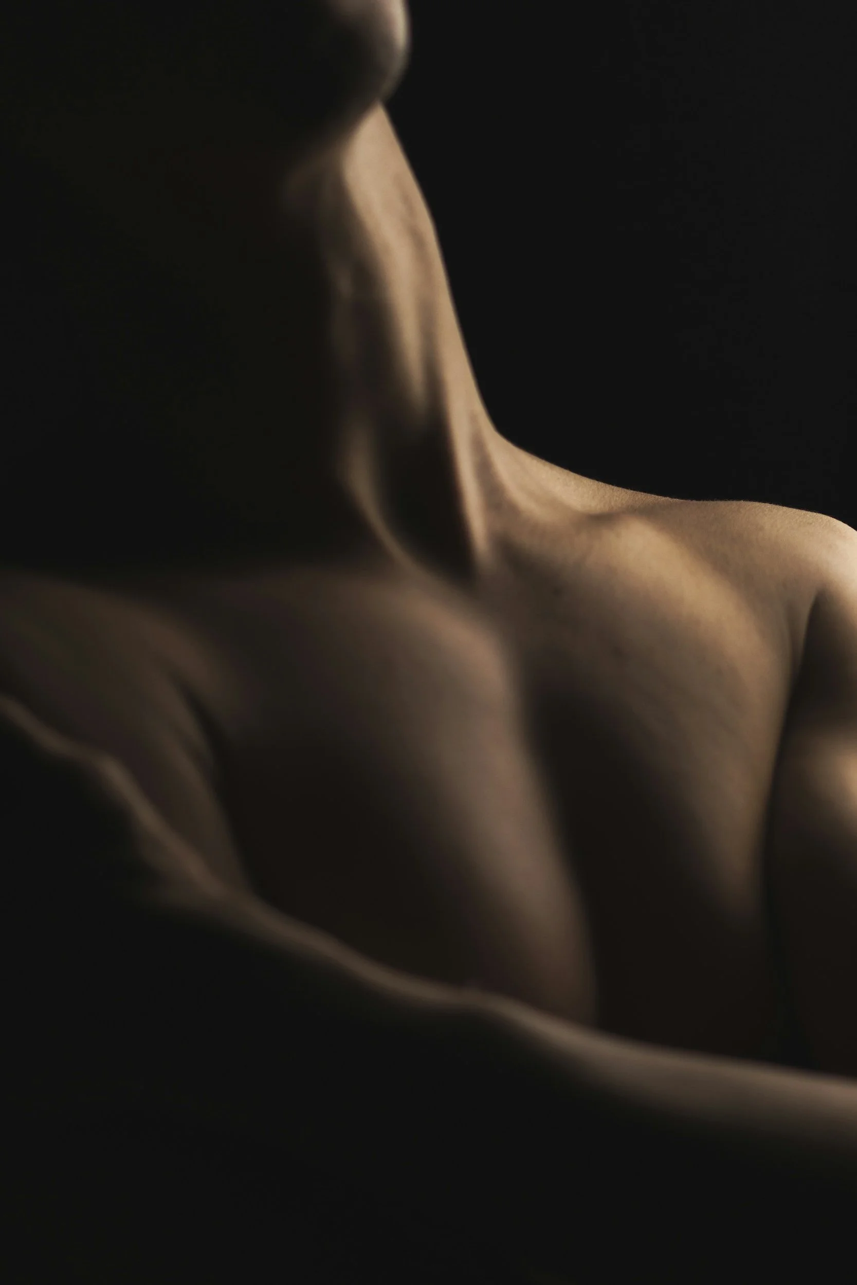 Somatic sexology and intimacy coaching for men and penis owners, showing a low-lit, grounded shot of body contours to highlight physical presence.