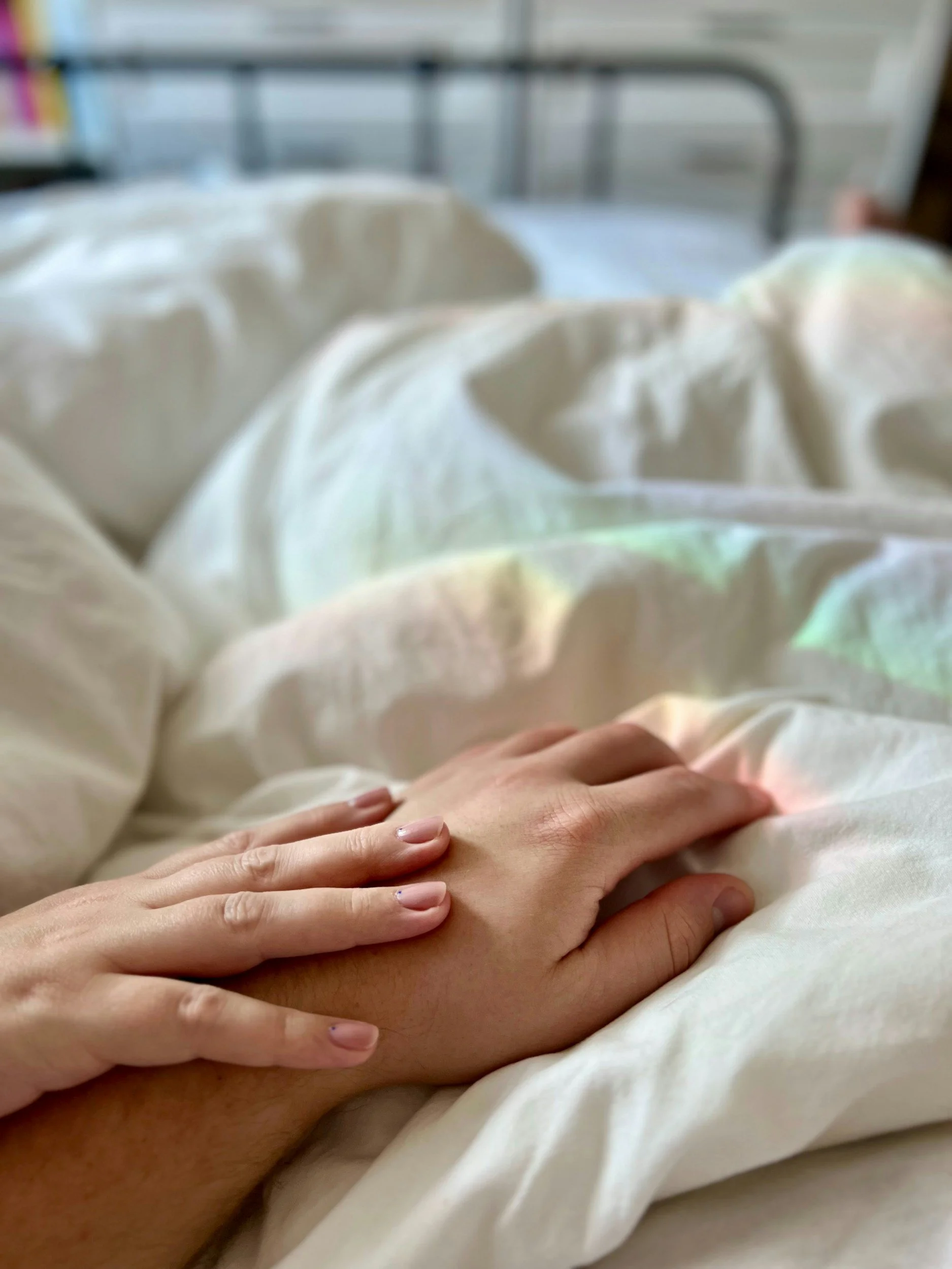 A supportive hand resting on a person's abdomen, representing trauma-informed somatic care and nervous system regulation.