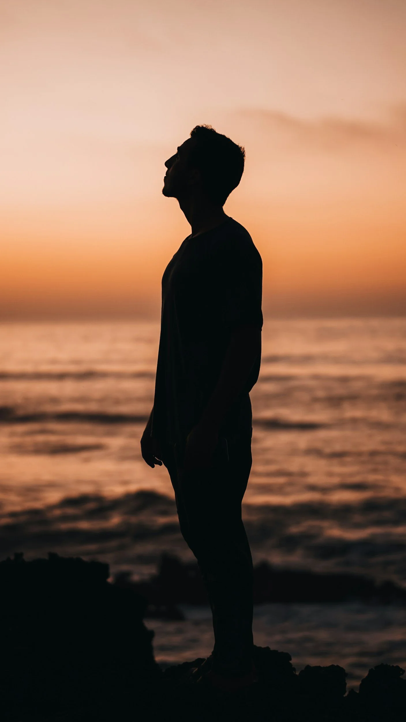 Silhouette of a person on a beach during a warm golden-hour sunset