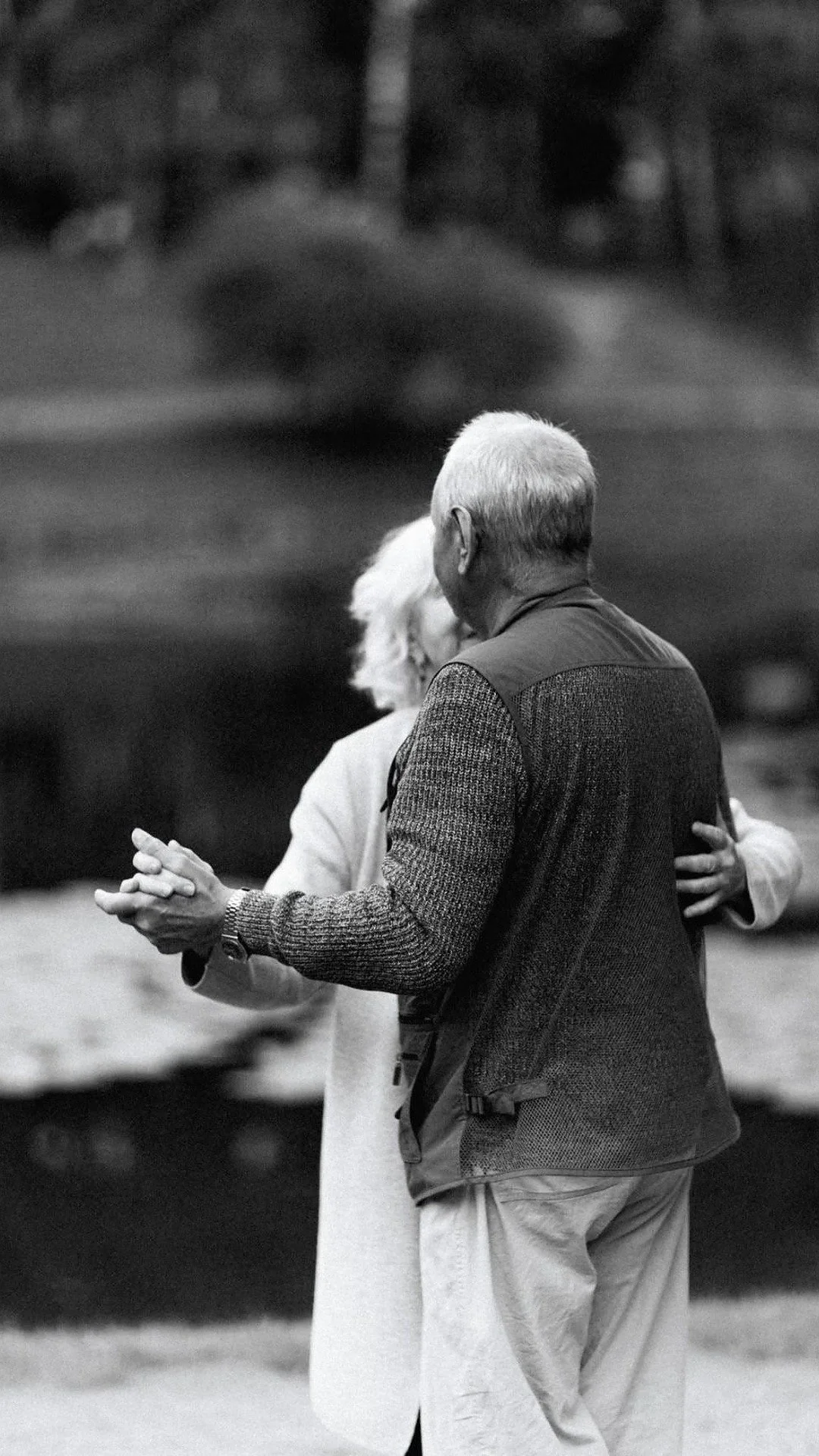 Mature couple holding hands and dancing outside, enjoying somatic connection and shared movement.