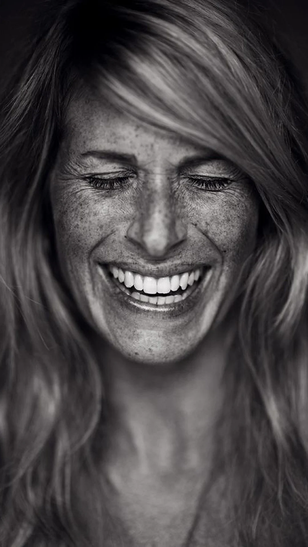 A joyful woman smiling with her hands touching her chin, embodying self-love and confidence.
