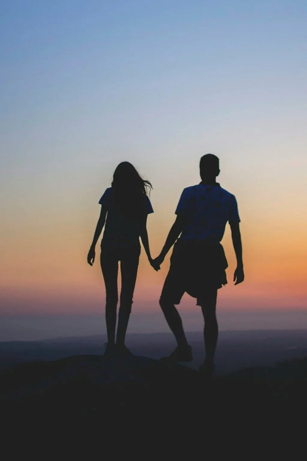 Silhouette of a couple holding hands at sunset, representing relational intimacy, connection, and navigating differences in desire through couples coaching.