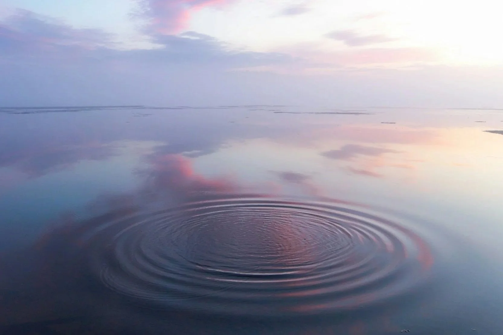 An abstract aerial view of soft water ripples at sunset, representing emotional grounding and the wave-like flow of physical arousal.