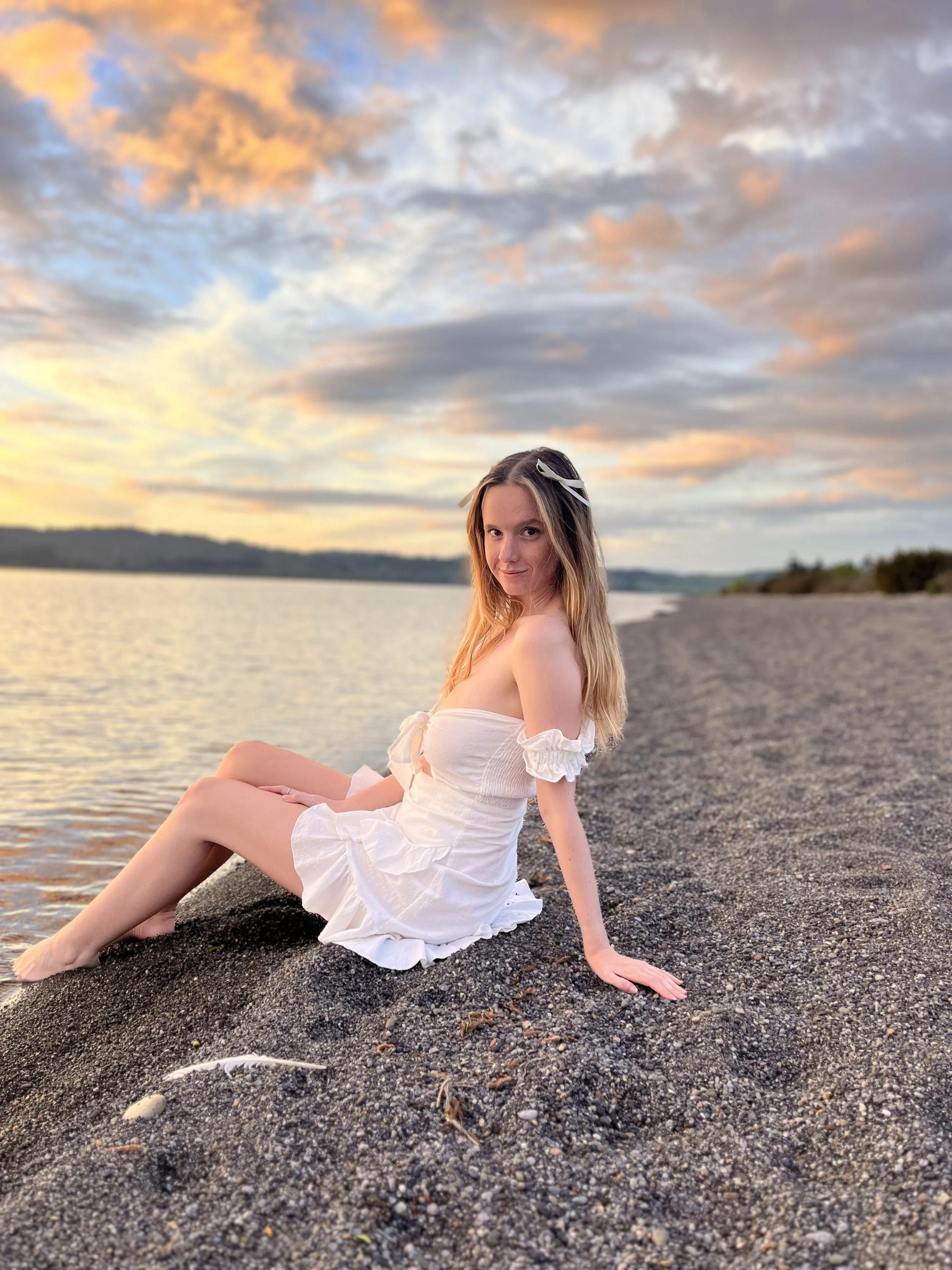 Michaela Tutty, Somatic Sex Coach, sitting by Lake Taupō. Online coaching available worldwide; local events in Taupō only.