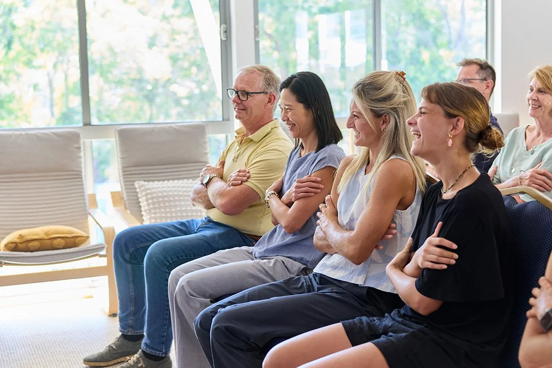 Group of people sitting and laughing in the mindingu retreat room during a mindfulness session